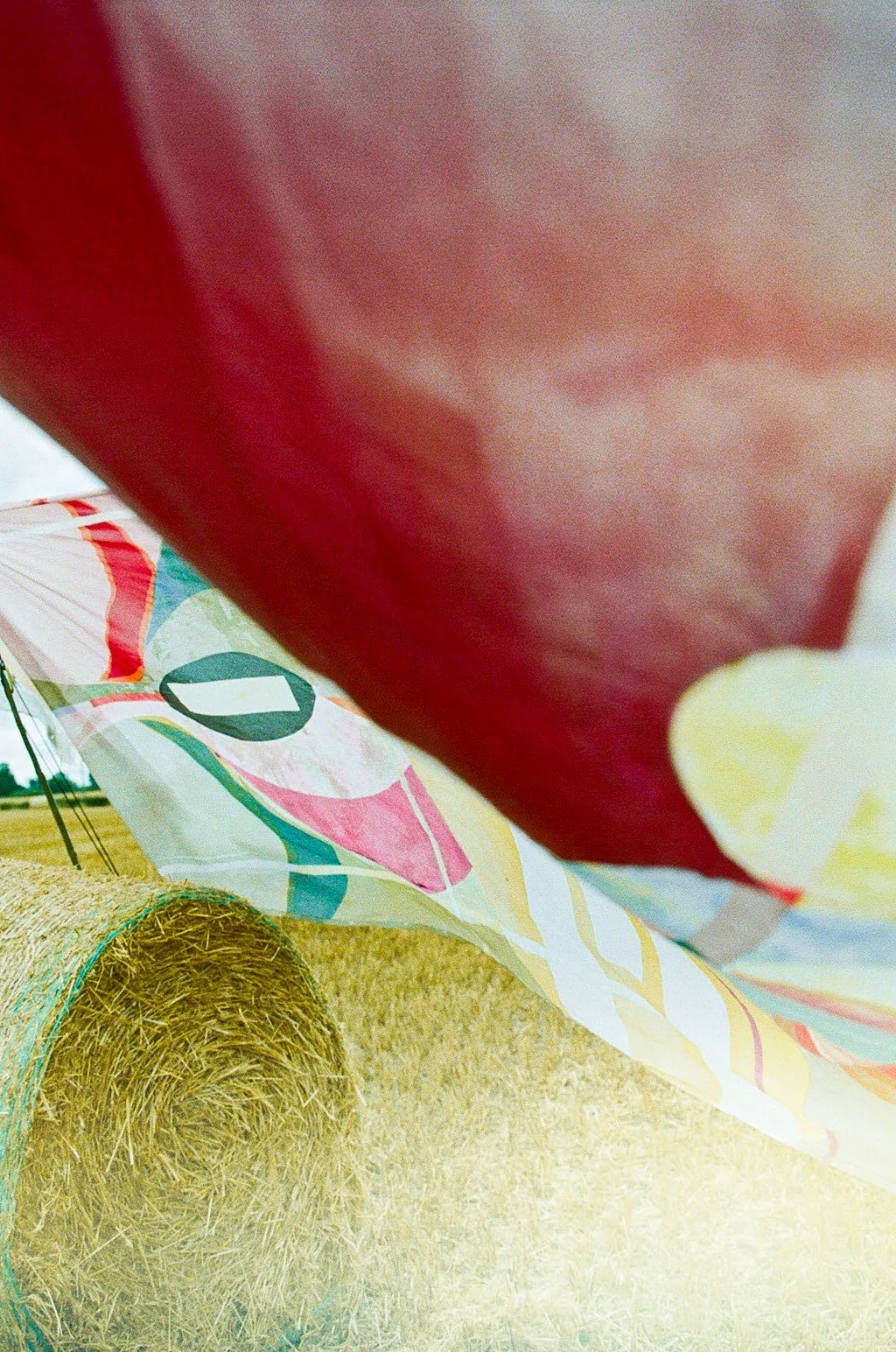 Close-up view of a colorful windmill and a hay bale in a field, with the photo taken under a tent or similar canopy.