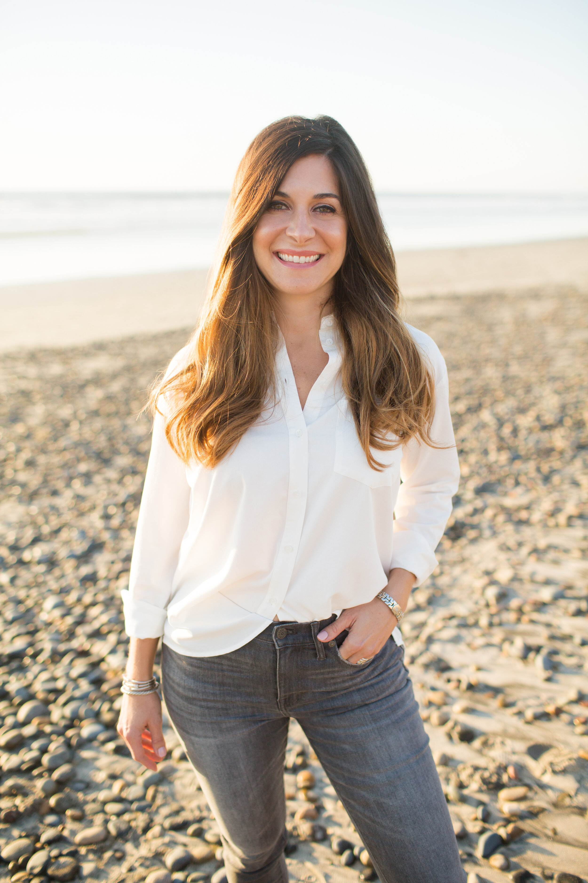 Ayren Pfeifer, Principal of The Pfeifer Team, smiling on the beach in a white button down shirt