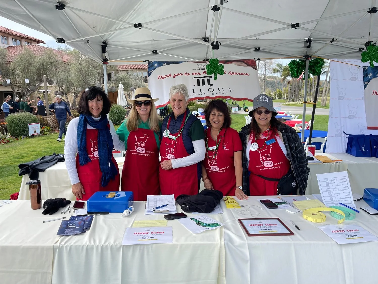 Freedom Dogs volunteers in red aprons at the check in table of the Freedom Dogs golf tournament