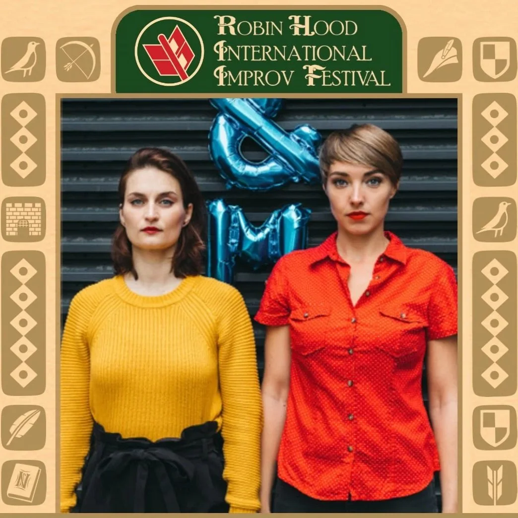 A picture of two improvisers on stage making claw shapes with their hands during a performance at the Robin Hood International Improv Festival in Nottingham