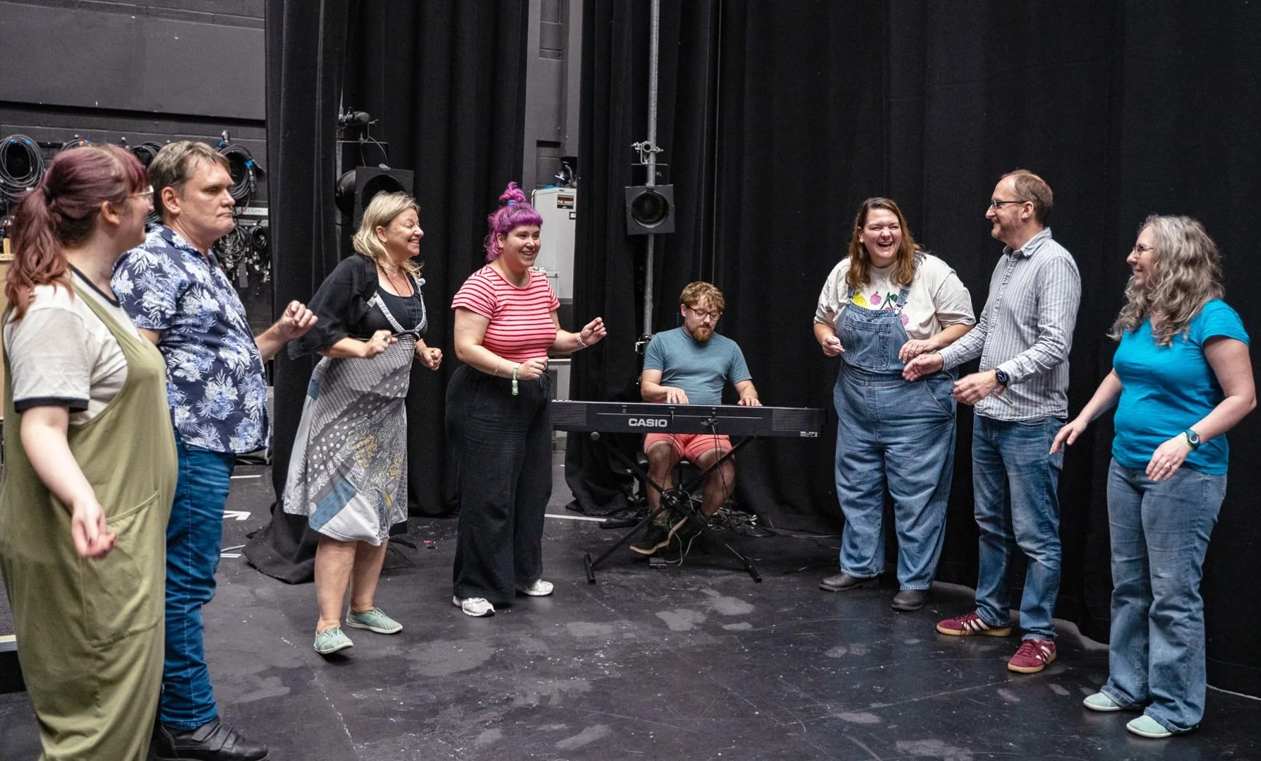 A group of musical improvisers gather around a keyboard