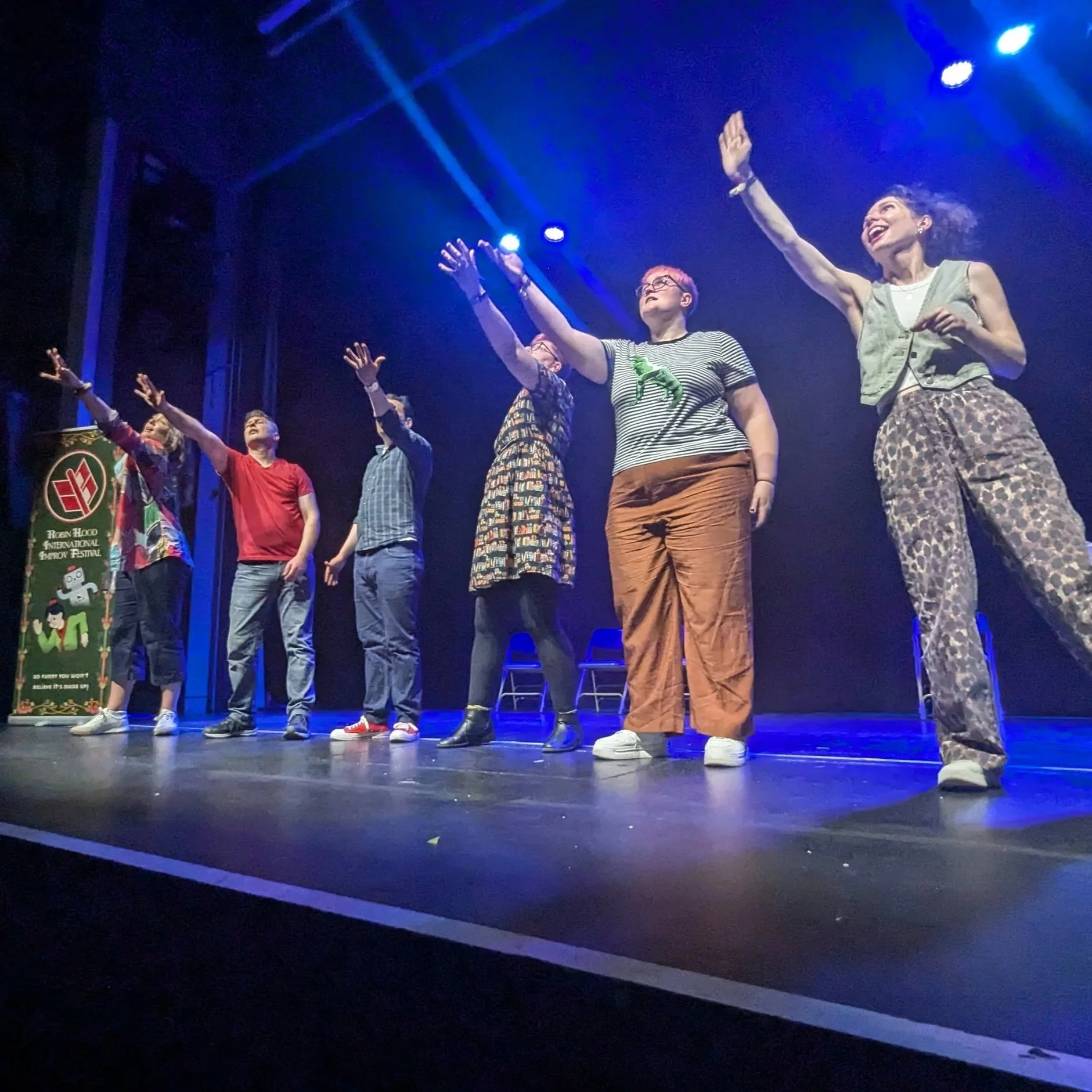 Performers on stage pointing upwards.