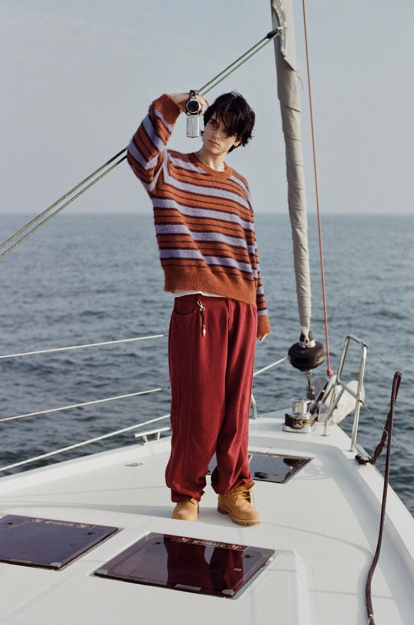 35mm film photograph of a male model holding a video camera on a yacht