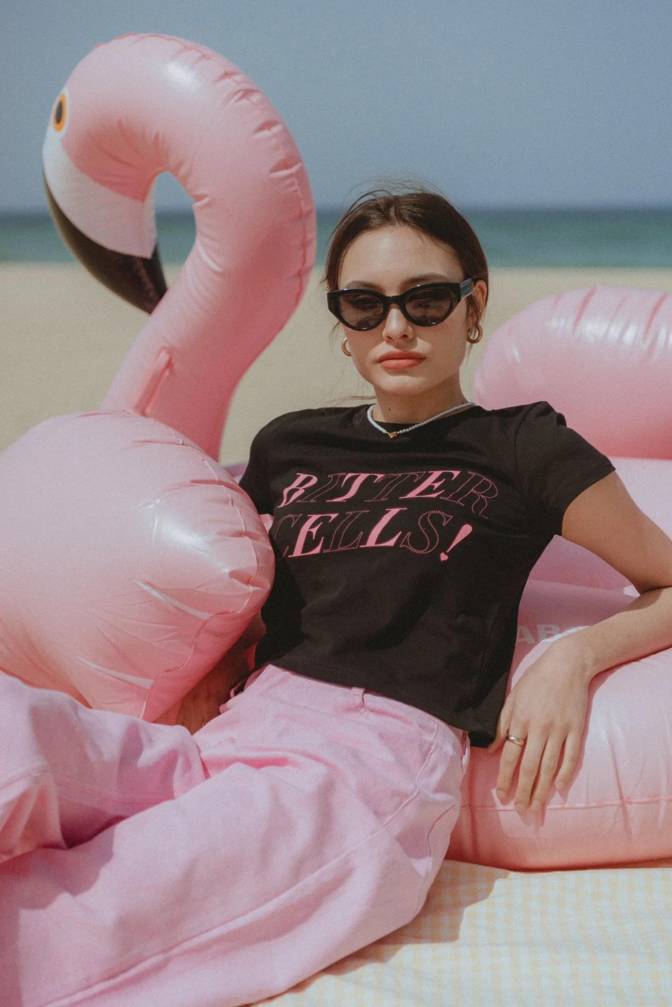 Lookbook photograph of a female model on an inflatable flamingo at the beach