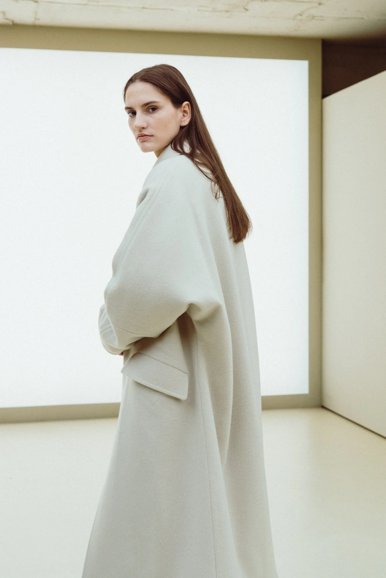 Minimal fashion photograph of a female model in an oversized coat