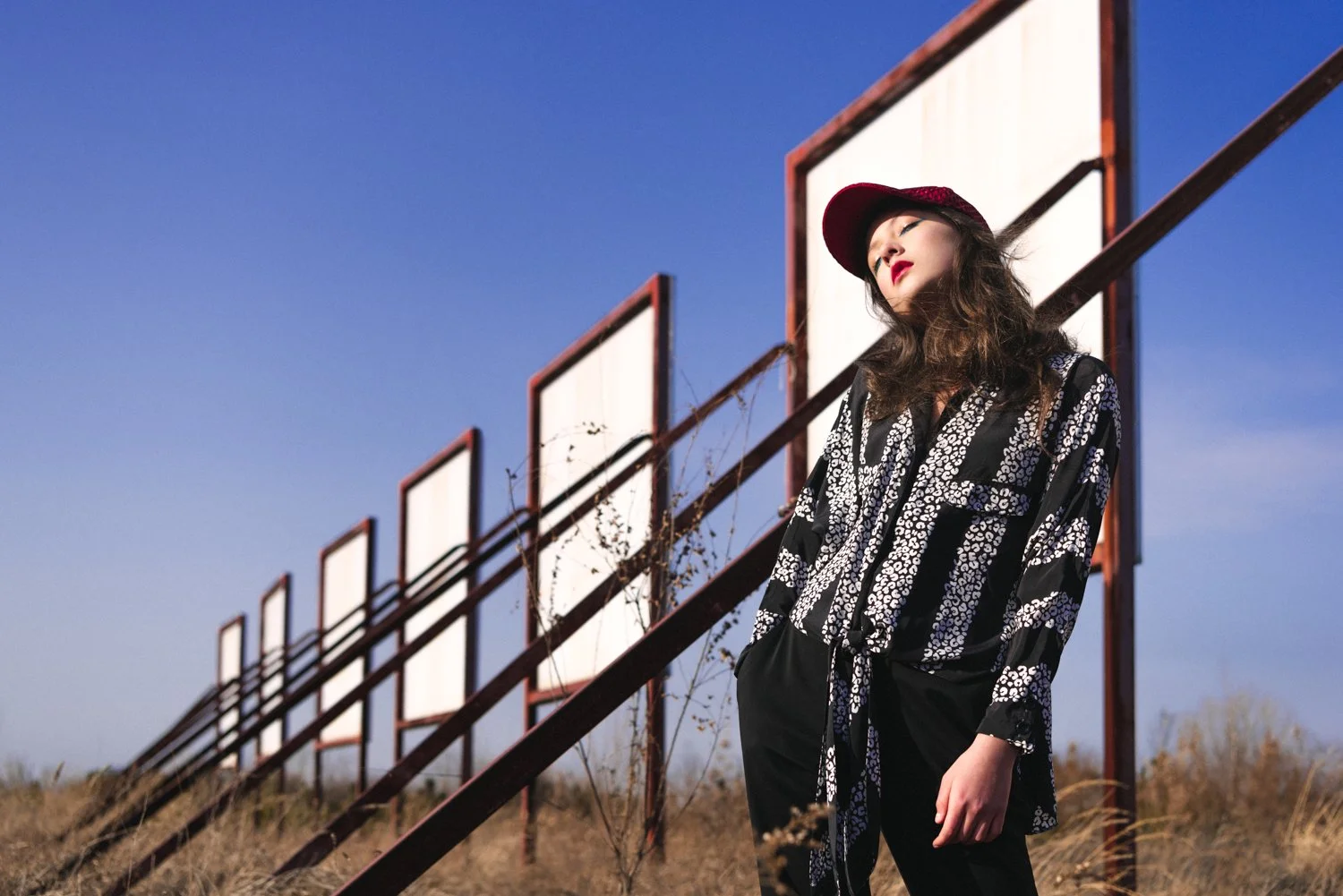 Fashion editorial photograph of a female model framed by a billboard