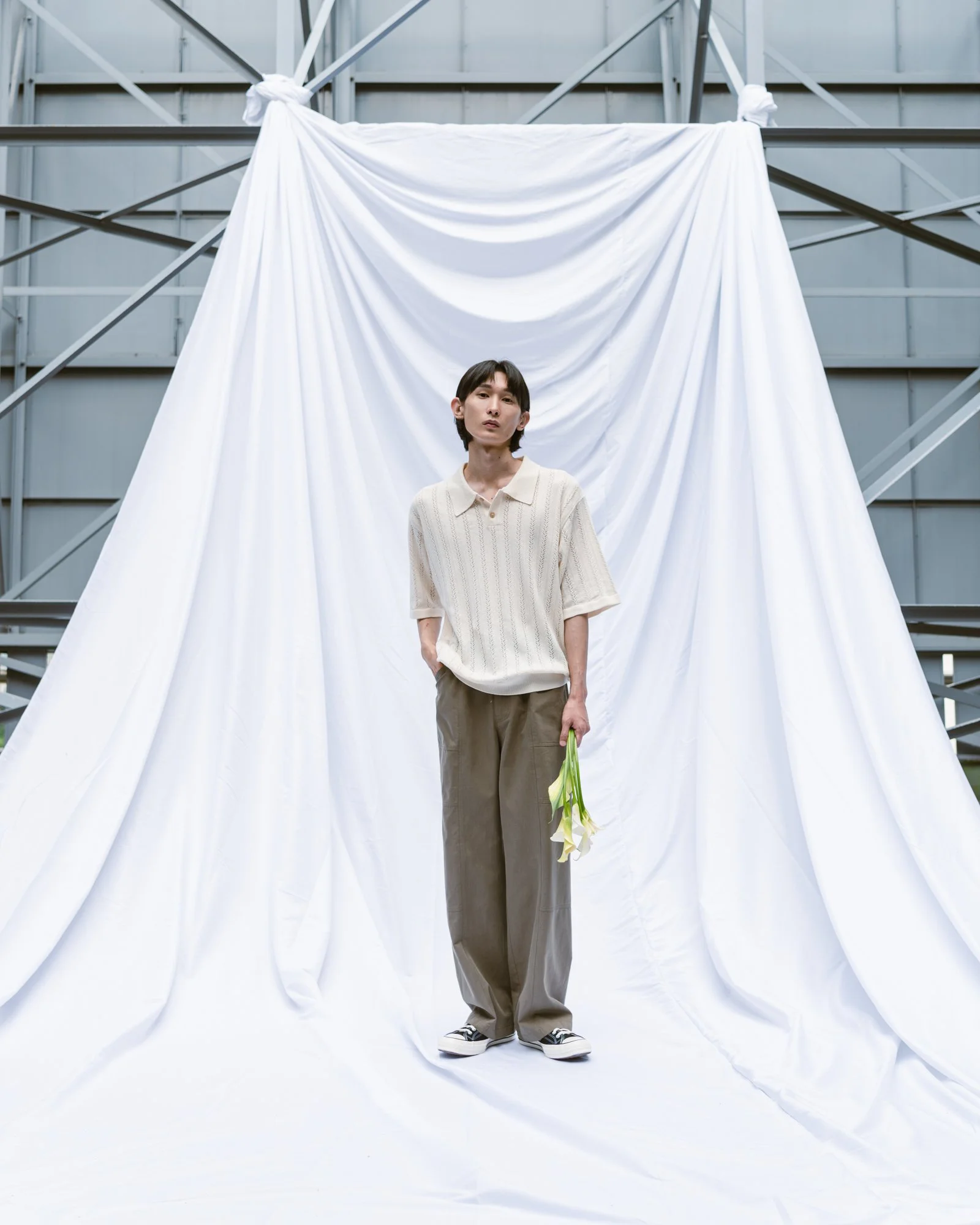 Photograph of a male model holding flowers on a fabric backdrop