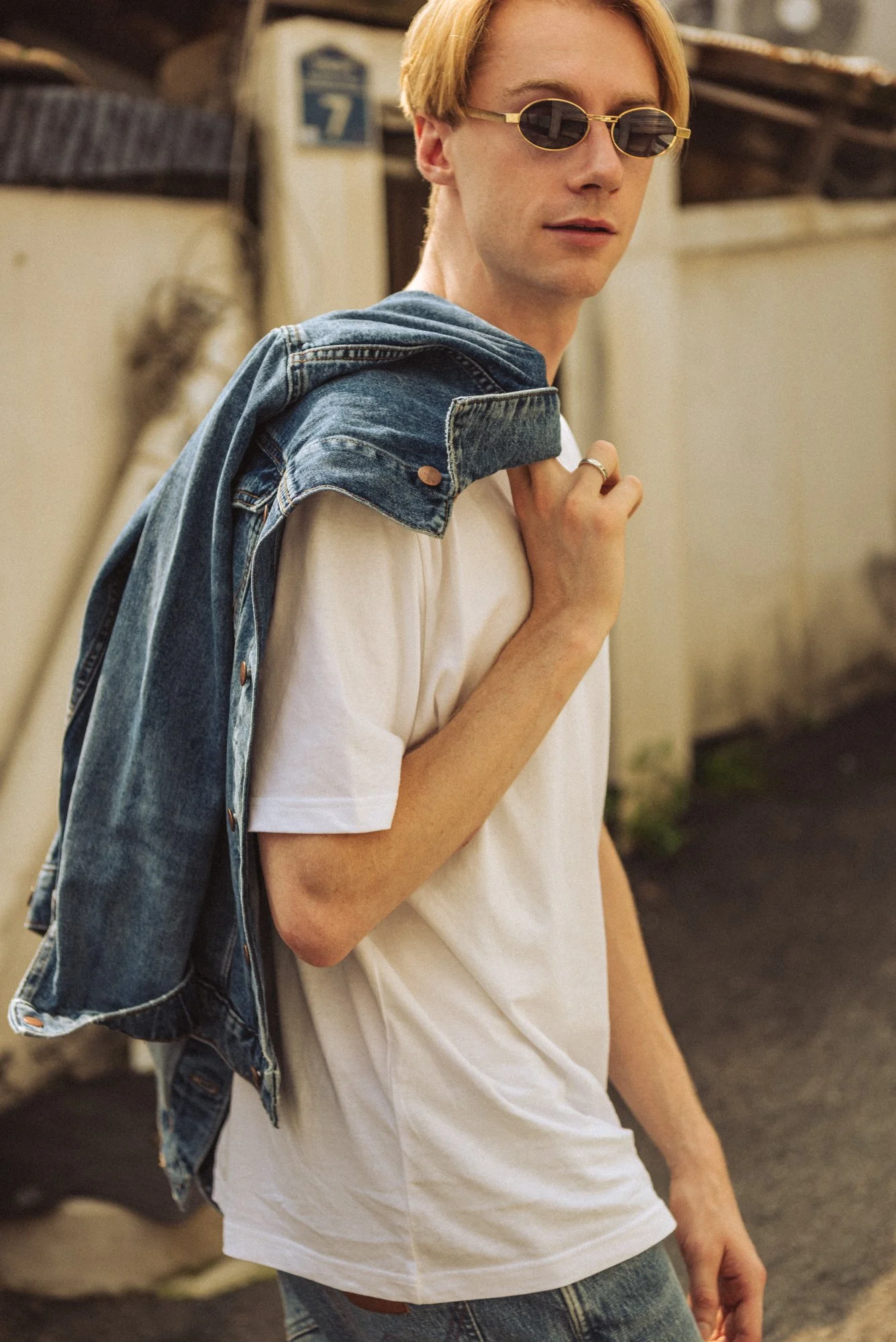 Photograph of a male model walking in Seoul with a denim jacket over his shoulder
