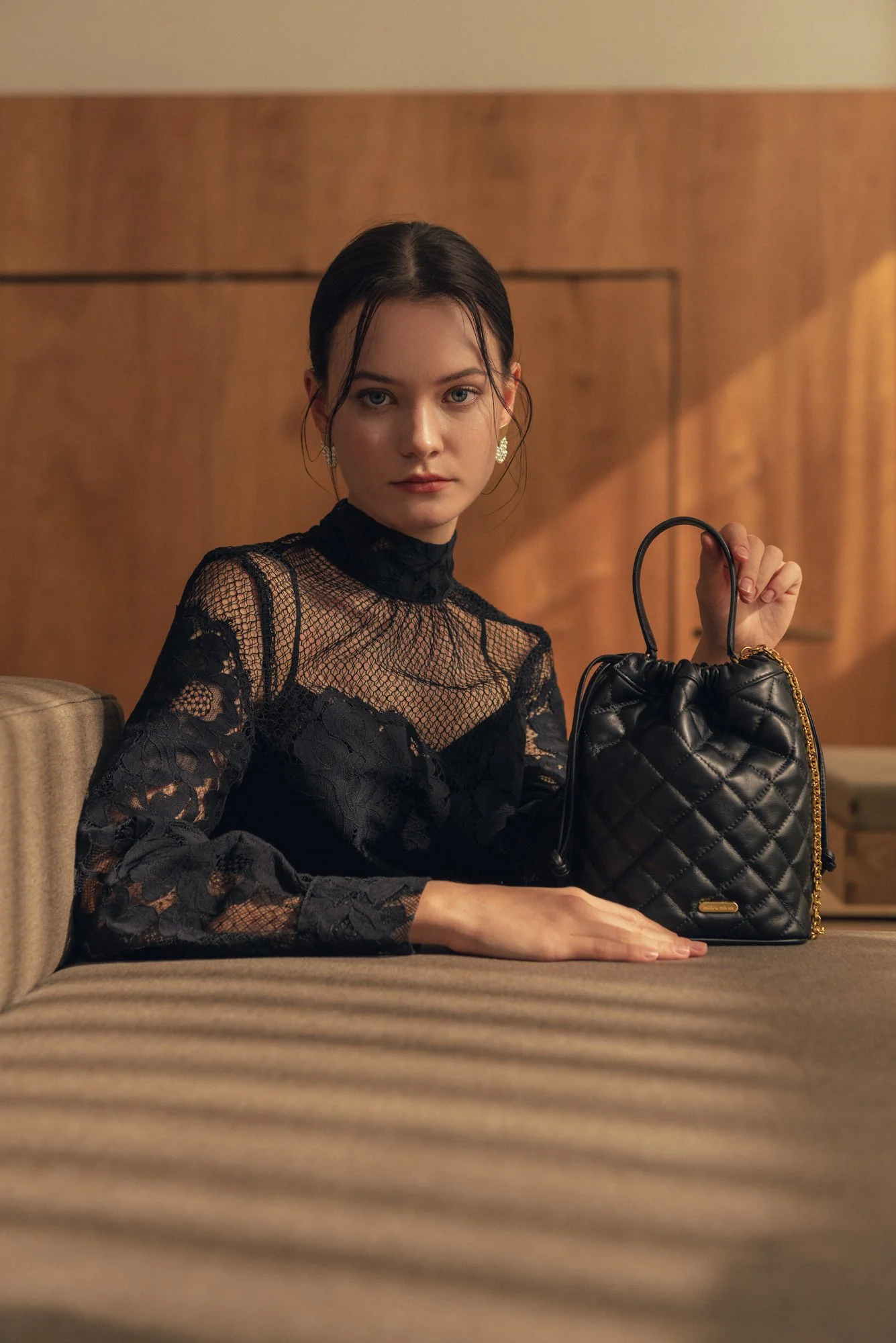 Lookbook photo of a female model in angled light holding a handbag