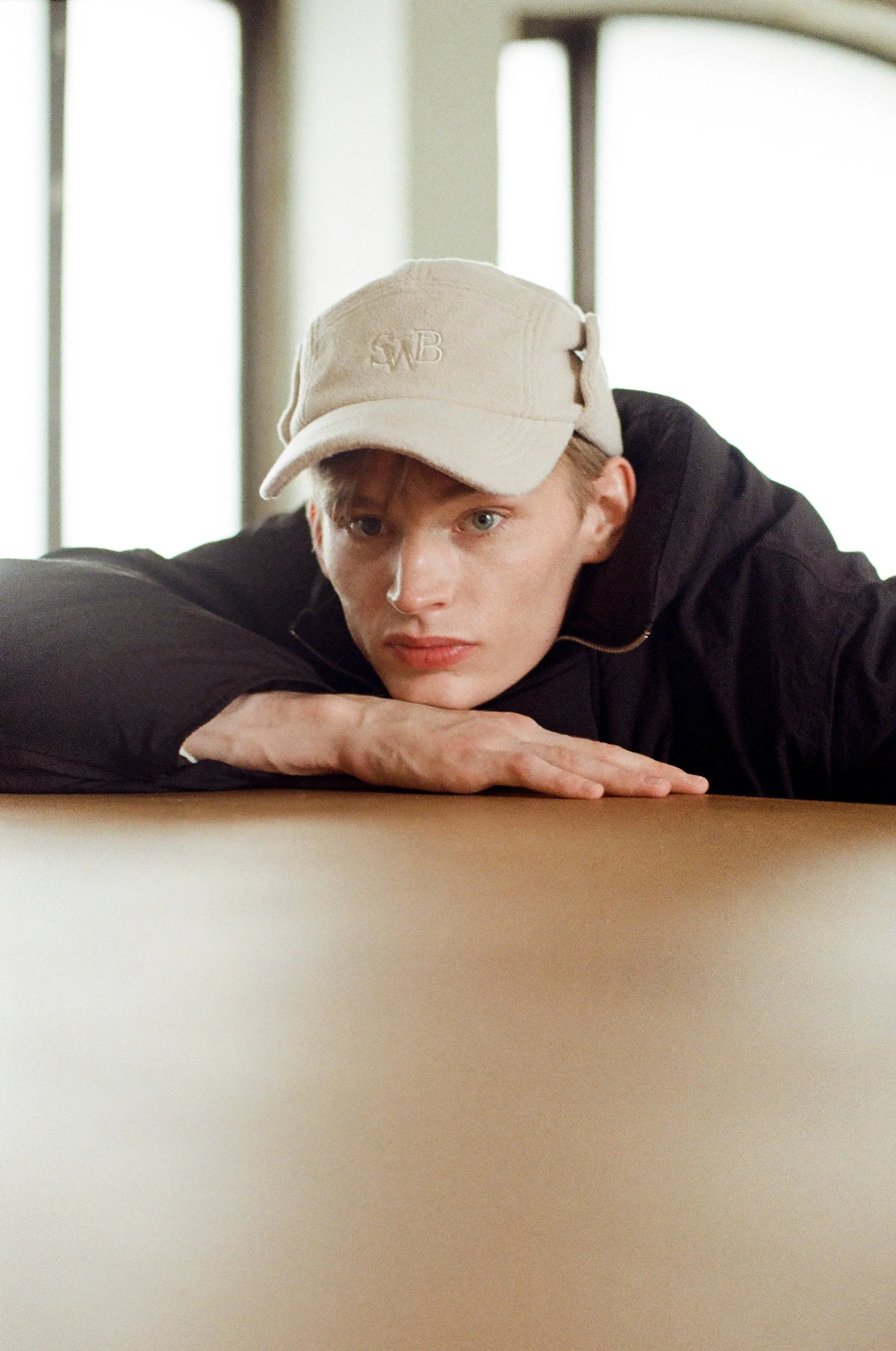 35mm film photograph of a male model in a cap leaning on a table