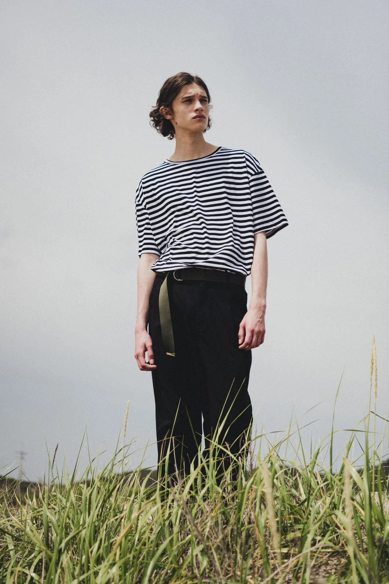 Outdoor fashion photograph of a male model standing on a hill