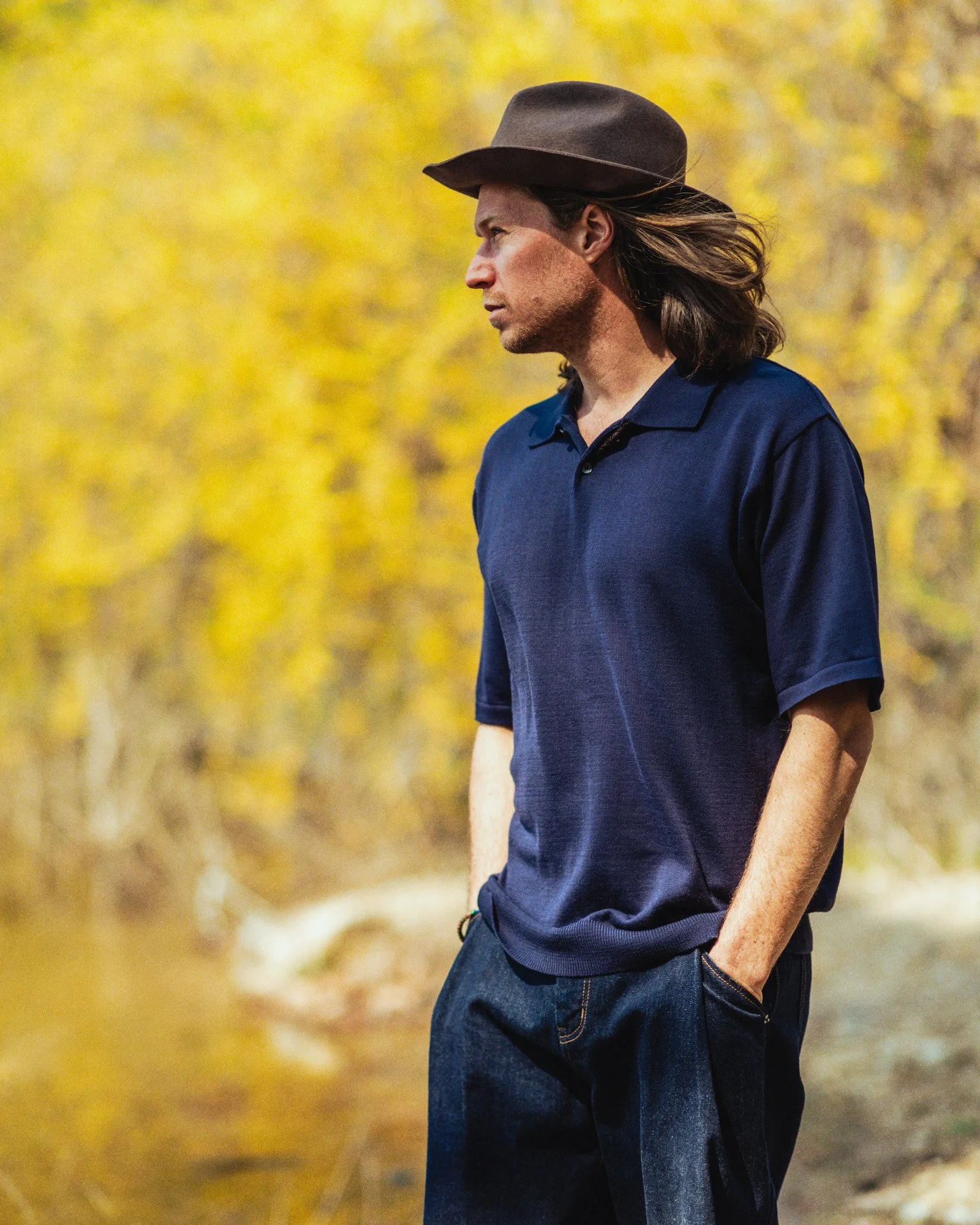 Outdoor fashion photograph of a male model against a background of yellow flowers