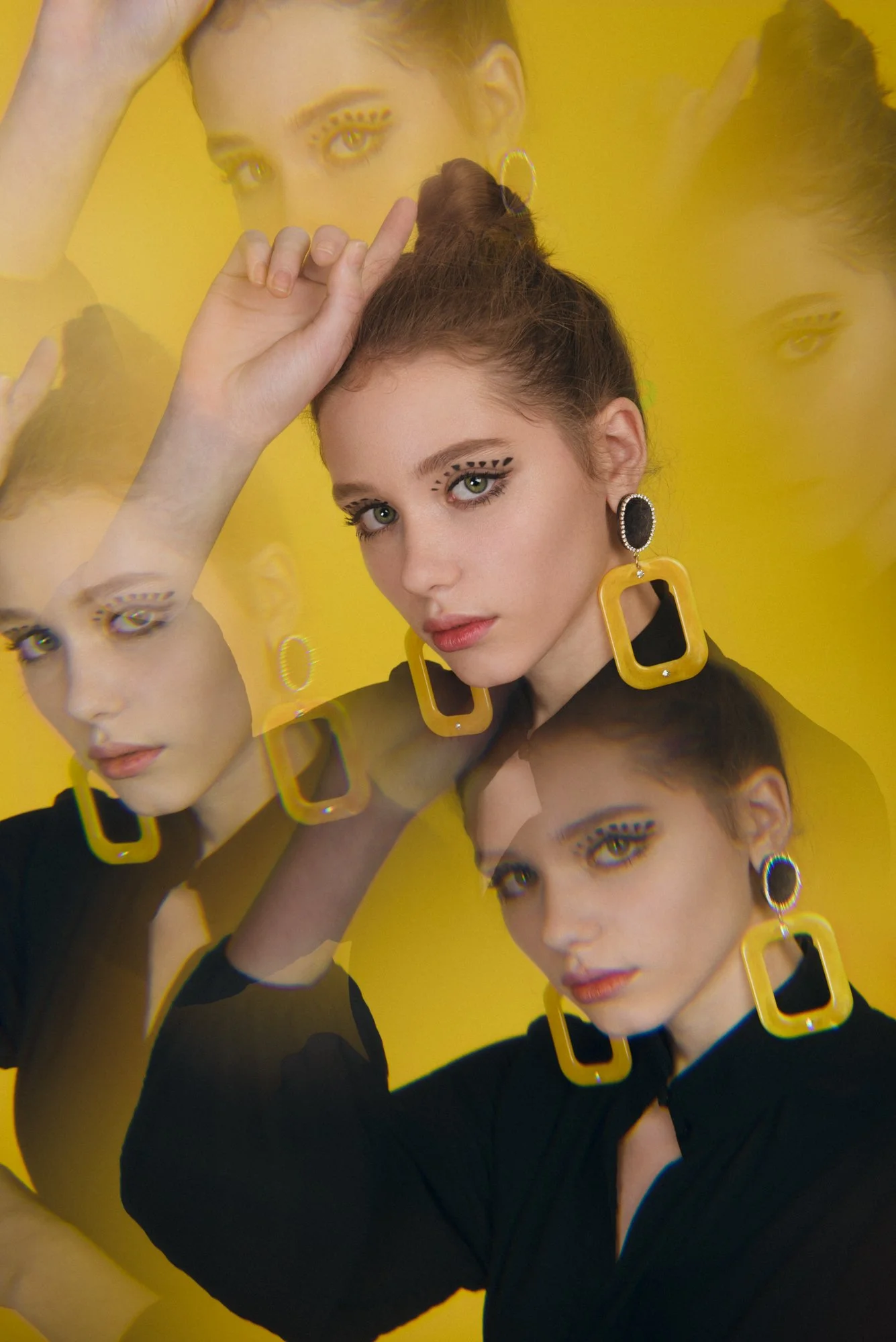 Kaleidoscopic photograph of a female model with yellow earrings on a yellow background
