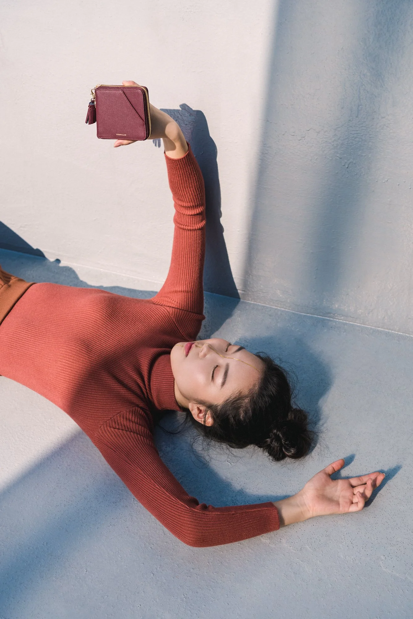 Fashion photograph of a Korean model lying down and holding a wallet