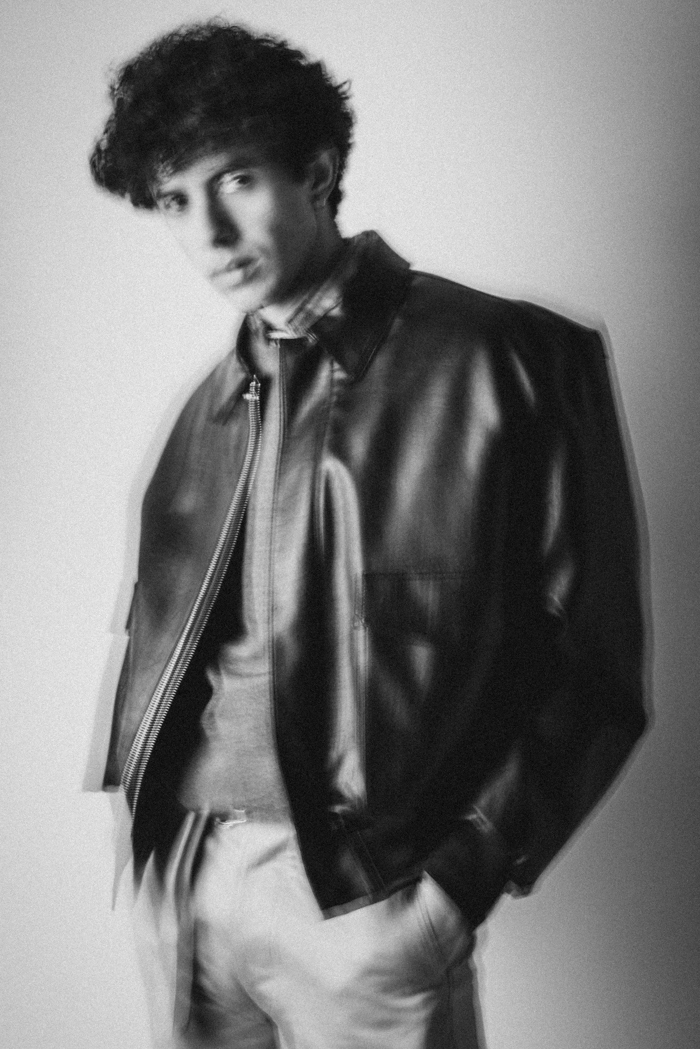 Black and white fashion photograph of a blurry model in a leather jacket