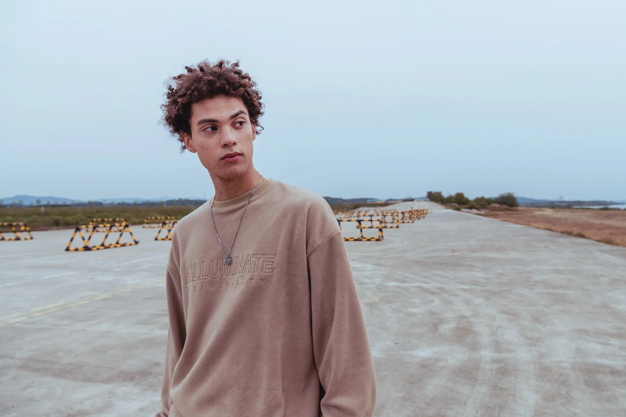 Landscape fashion photograph of a male model on an abandoned road