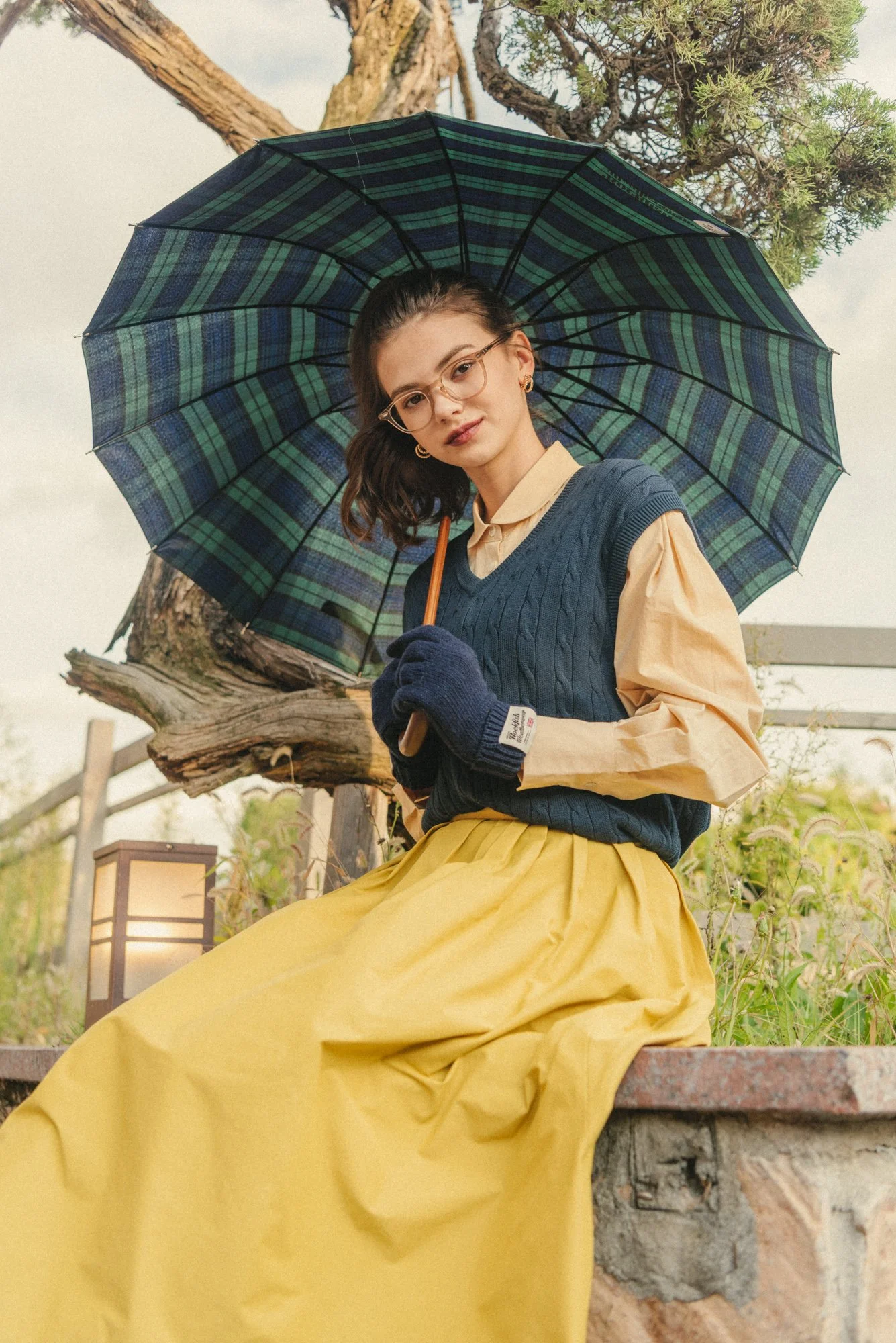 Lookbook photograph of a woman with an umbrella in a garden