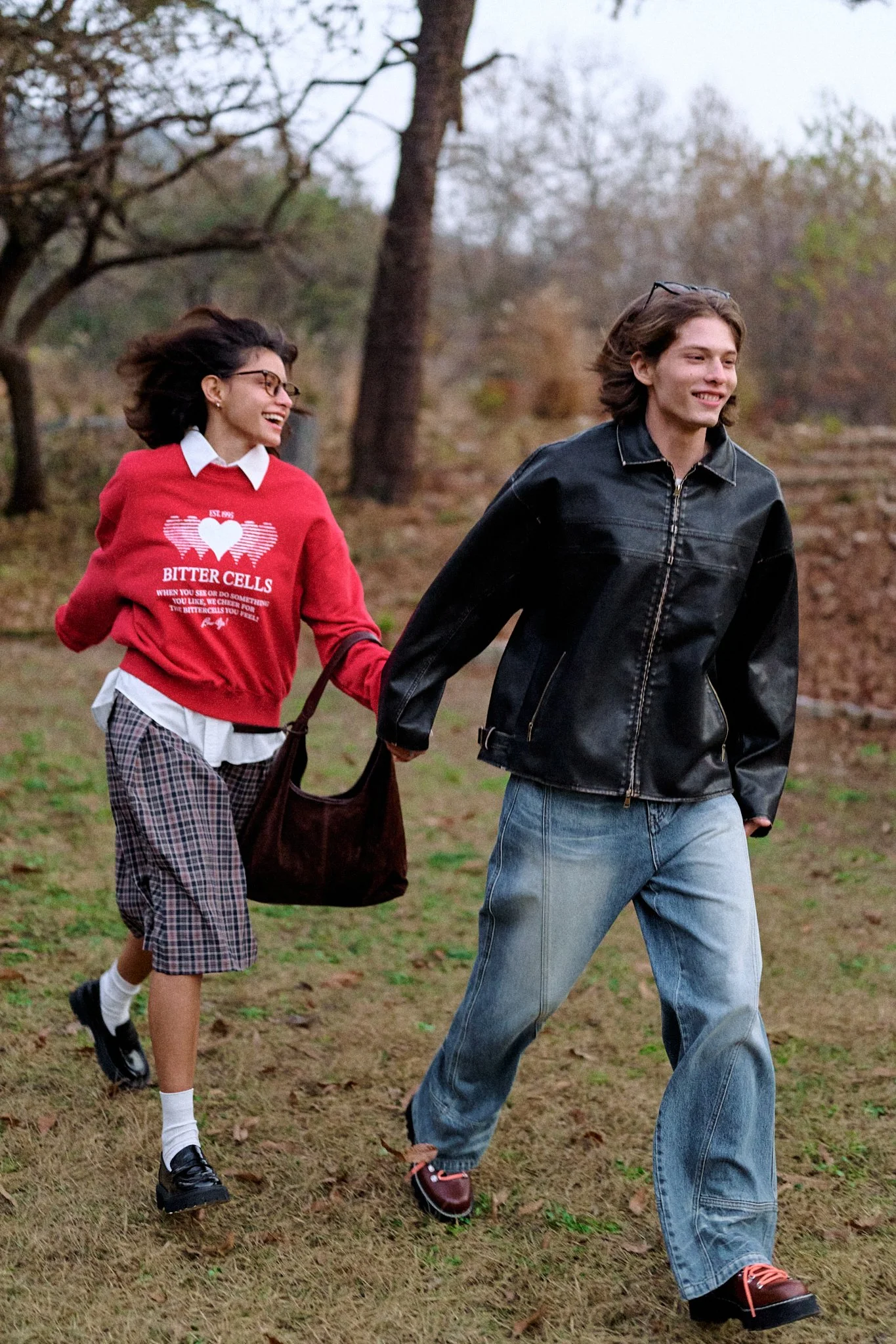 Photograph of two happy models holding hands and running