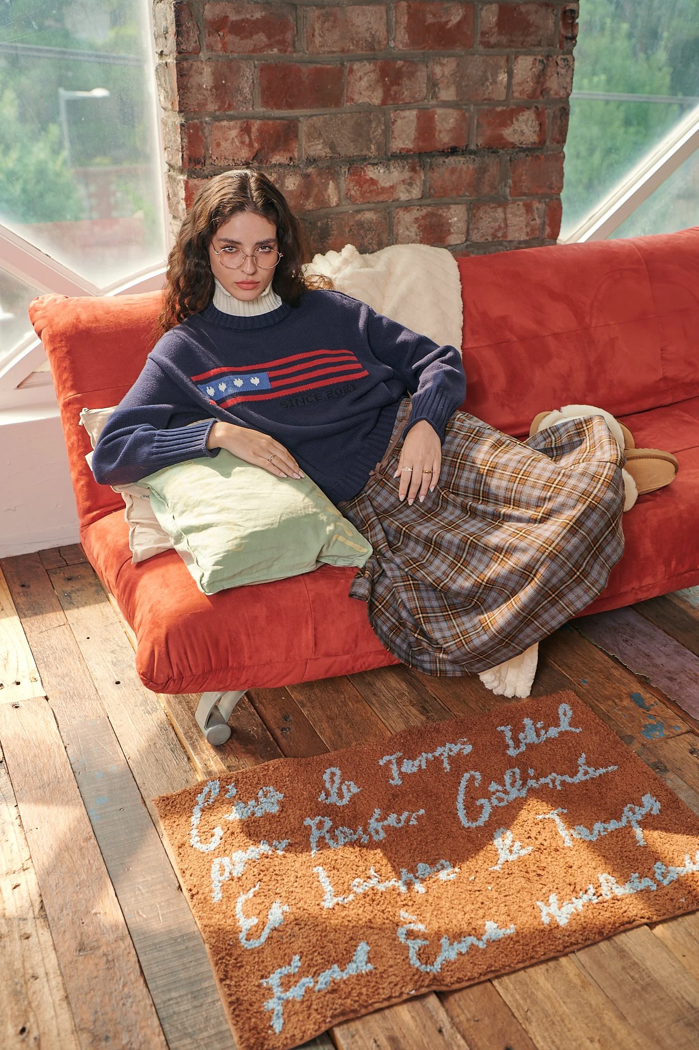 Lookbook photograph of a female model sitting on a couch