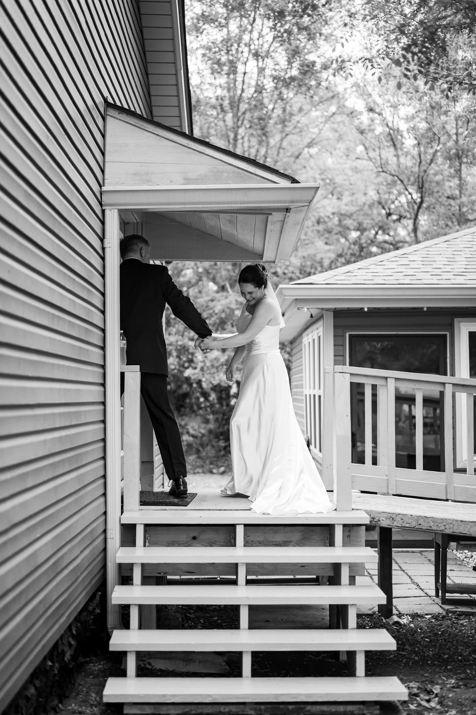 A black and white photo of a bride and groom on a wooden porch following their backyard wedding in Louisiana.