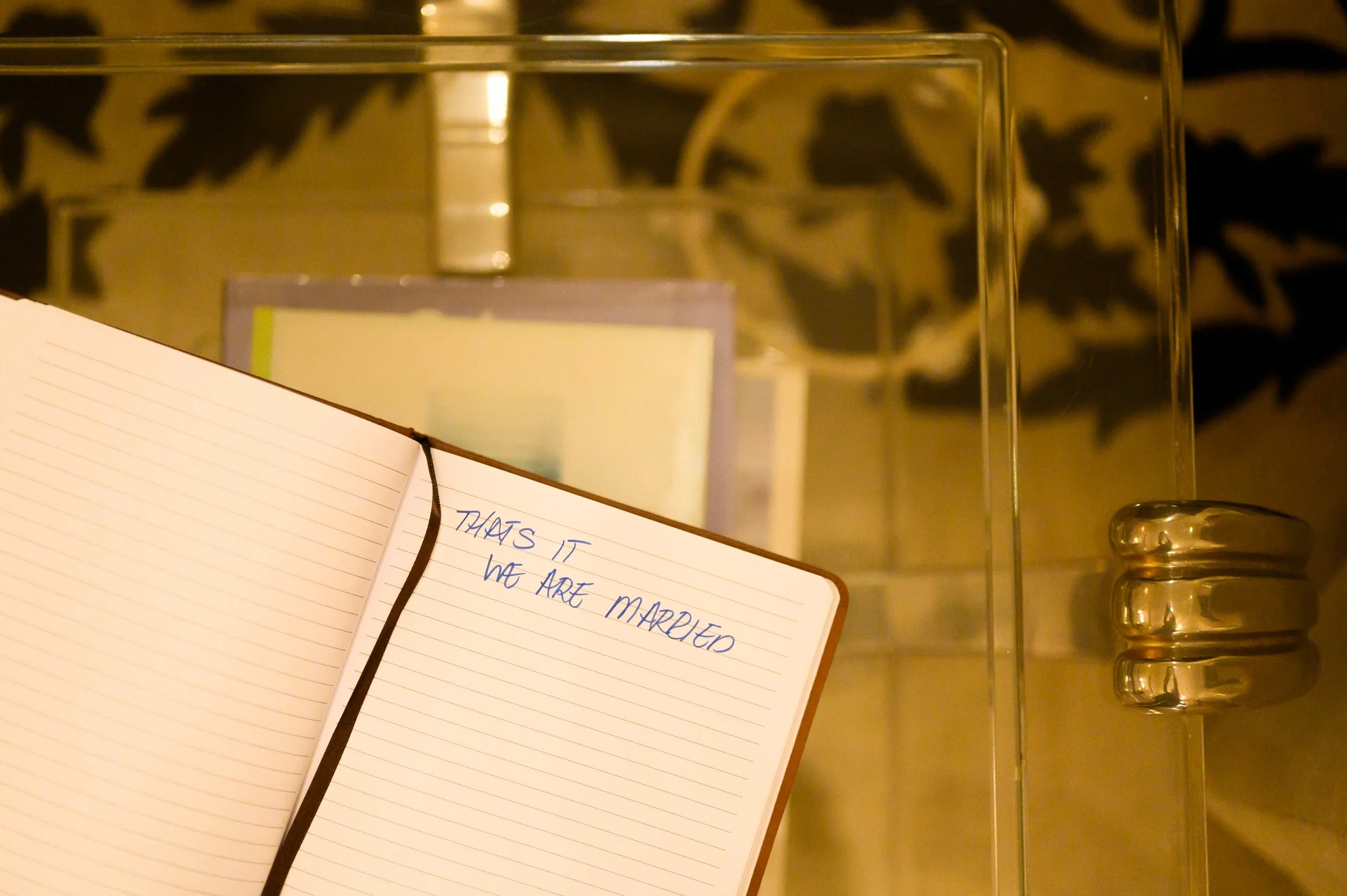 Open notebook with handwritten vows that reads, 'THAT'S IT WE ARE MARRIED'.
