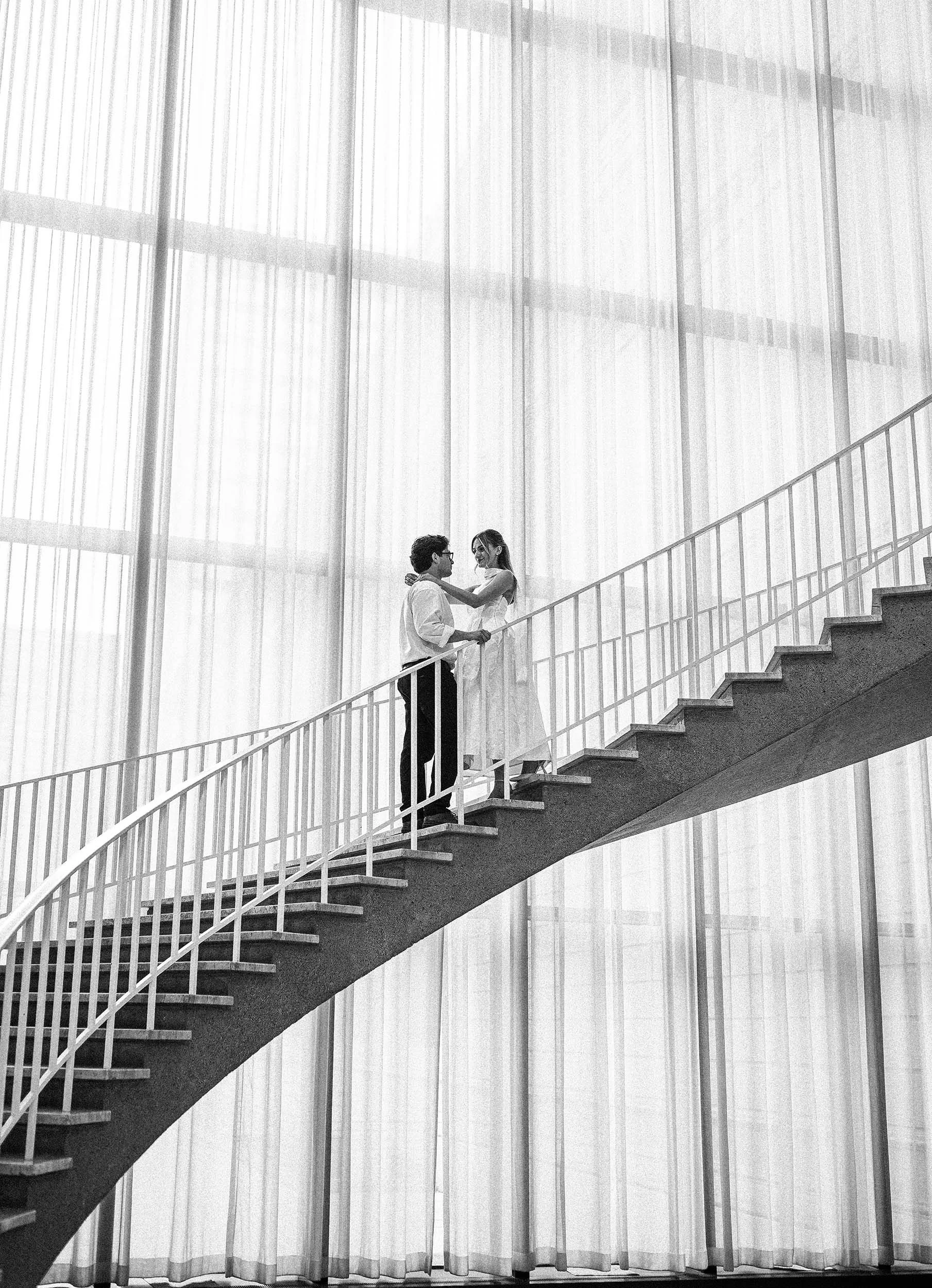 A black-and-white photo of an engaged couple on a long staircase at the Art Institute of Chicago.