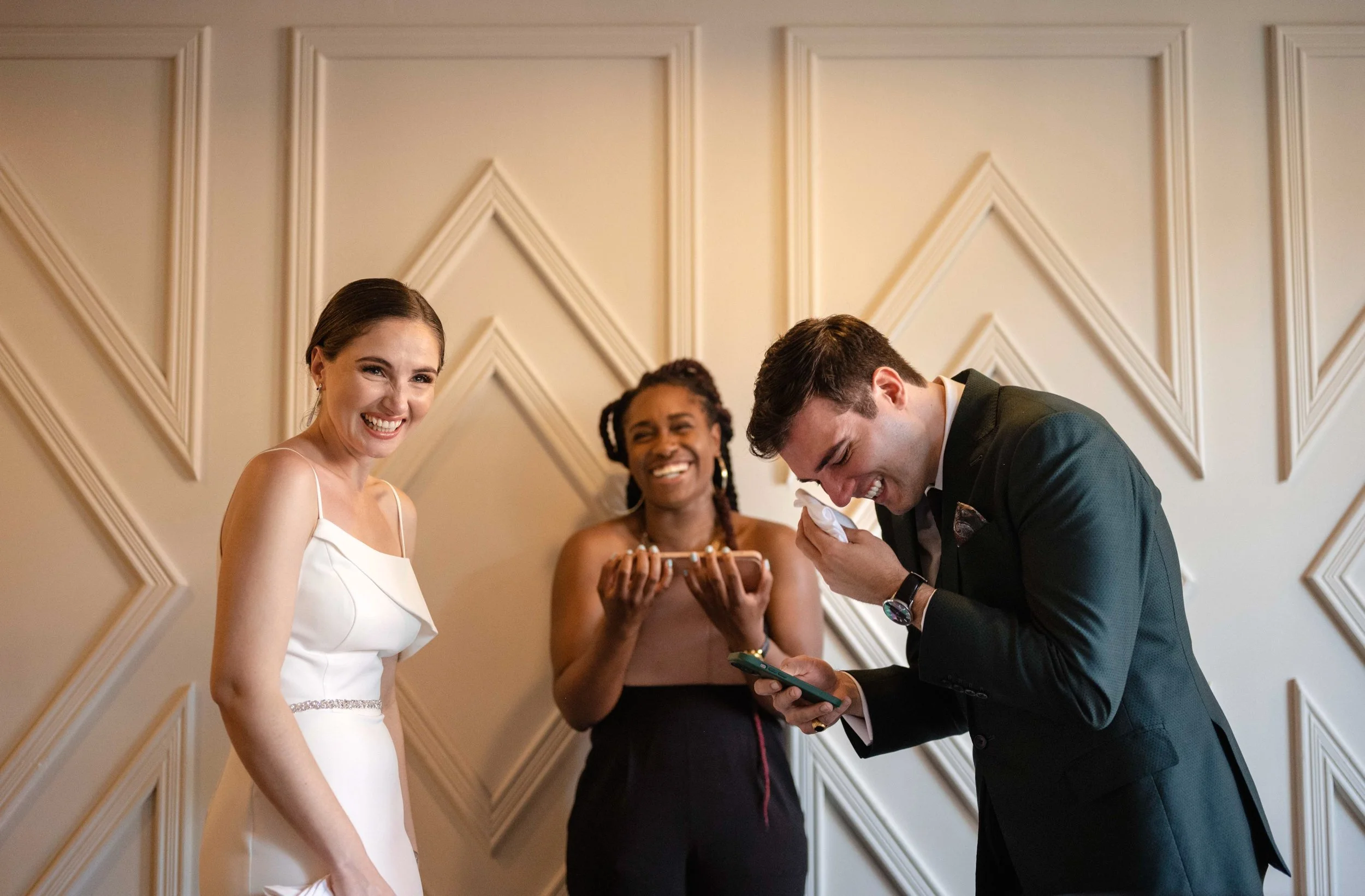 A bride, groom, and officiant laughing during the wedding ceremony.