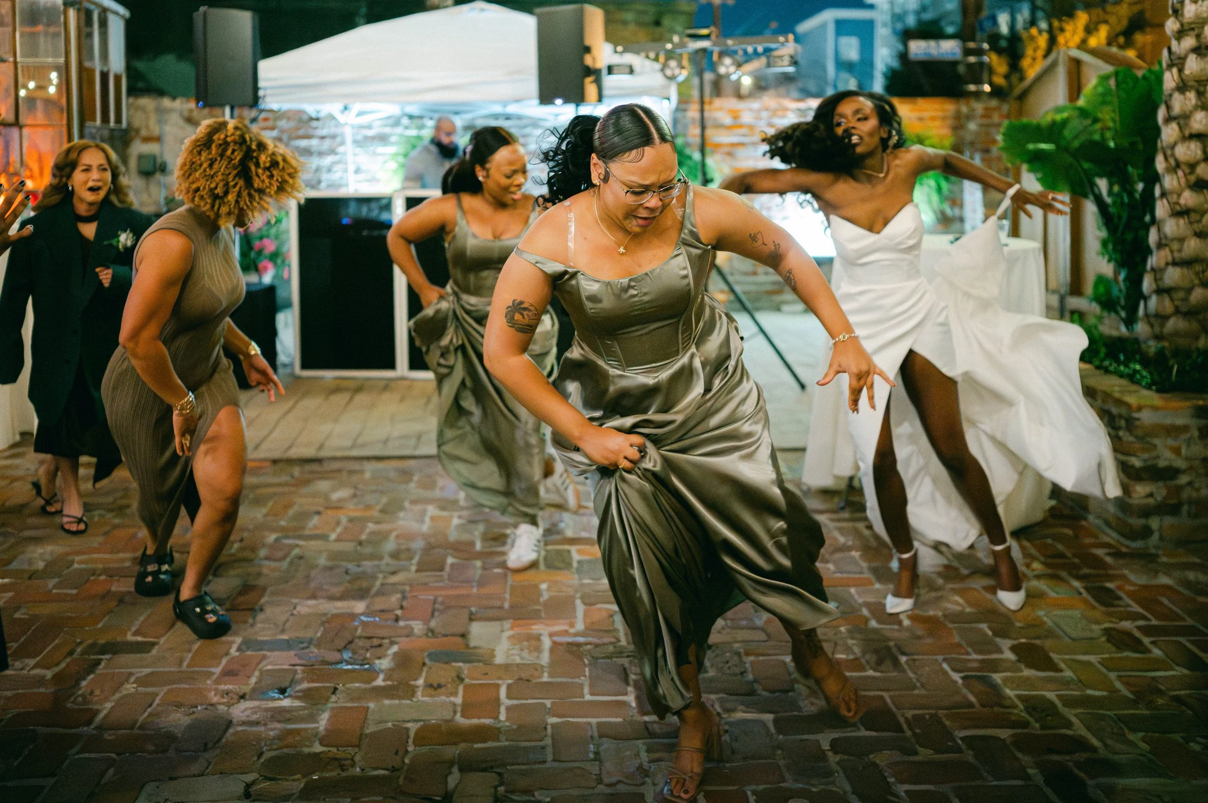 Group of women dancing at a wedding in a New Orleans courtyard.