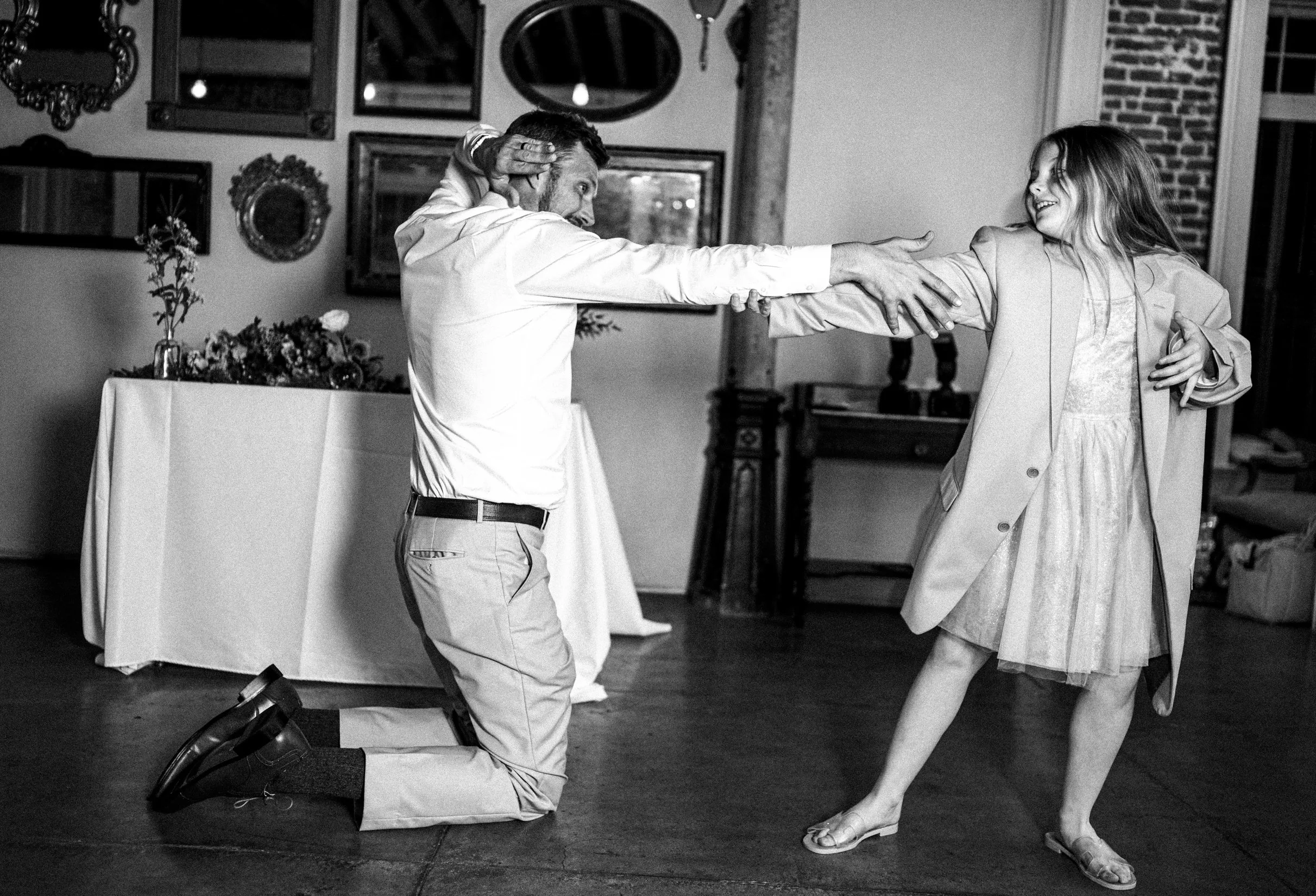 A father and daughter dance and laugh playfully during a wedding reception.