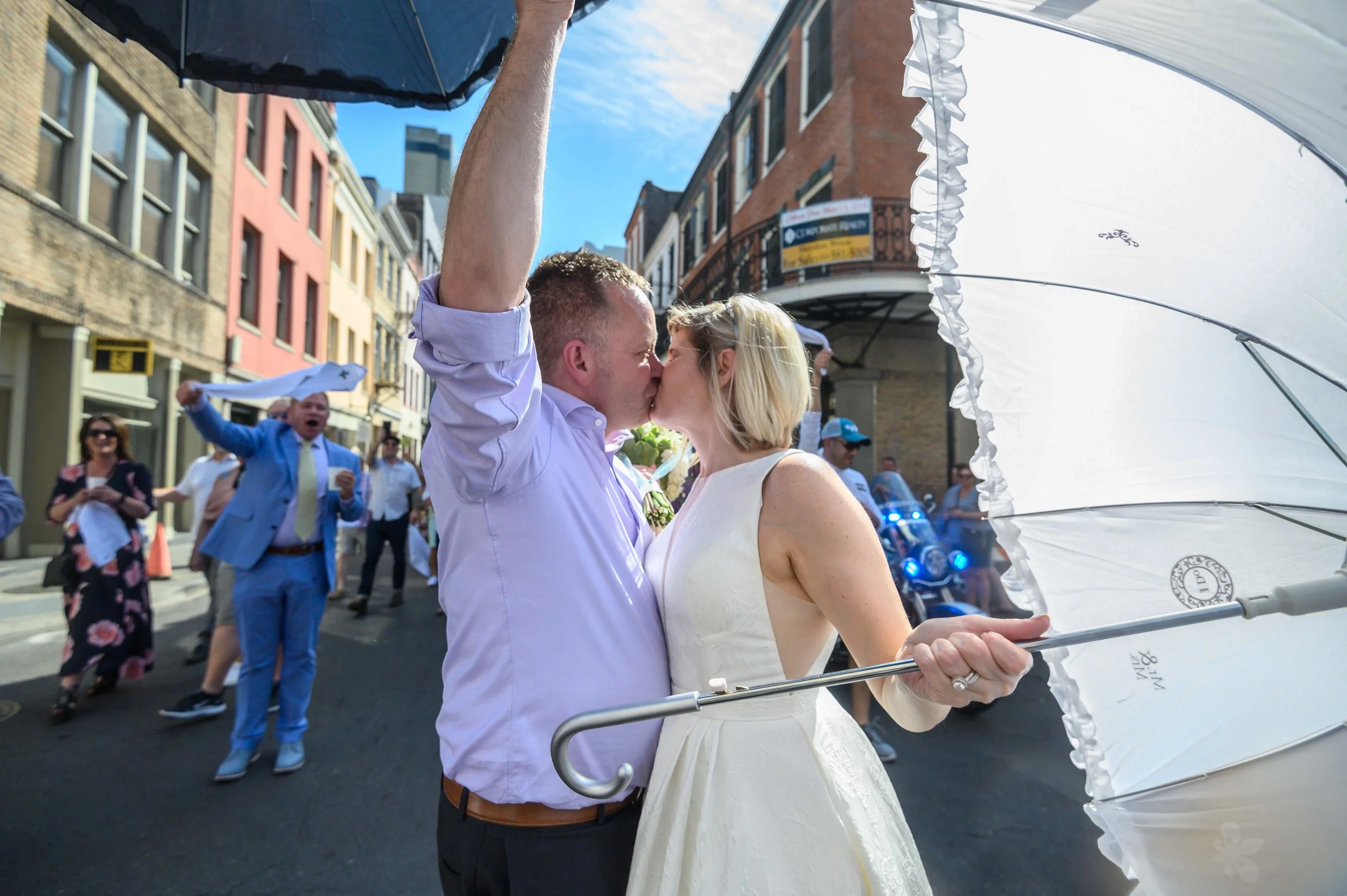 A bride and groom sharing a kiss during their wedding second line in New Orleans French Quarter.