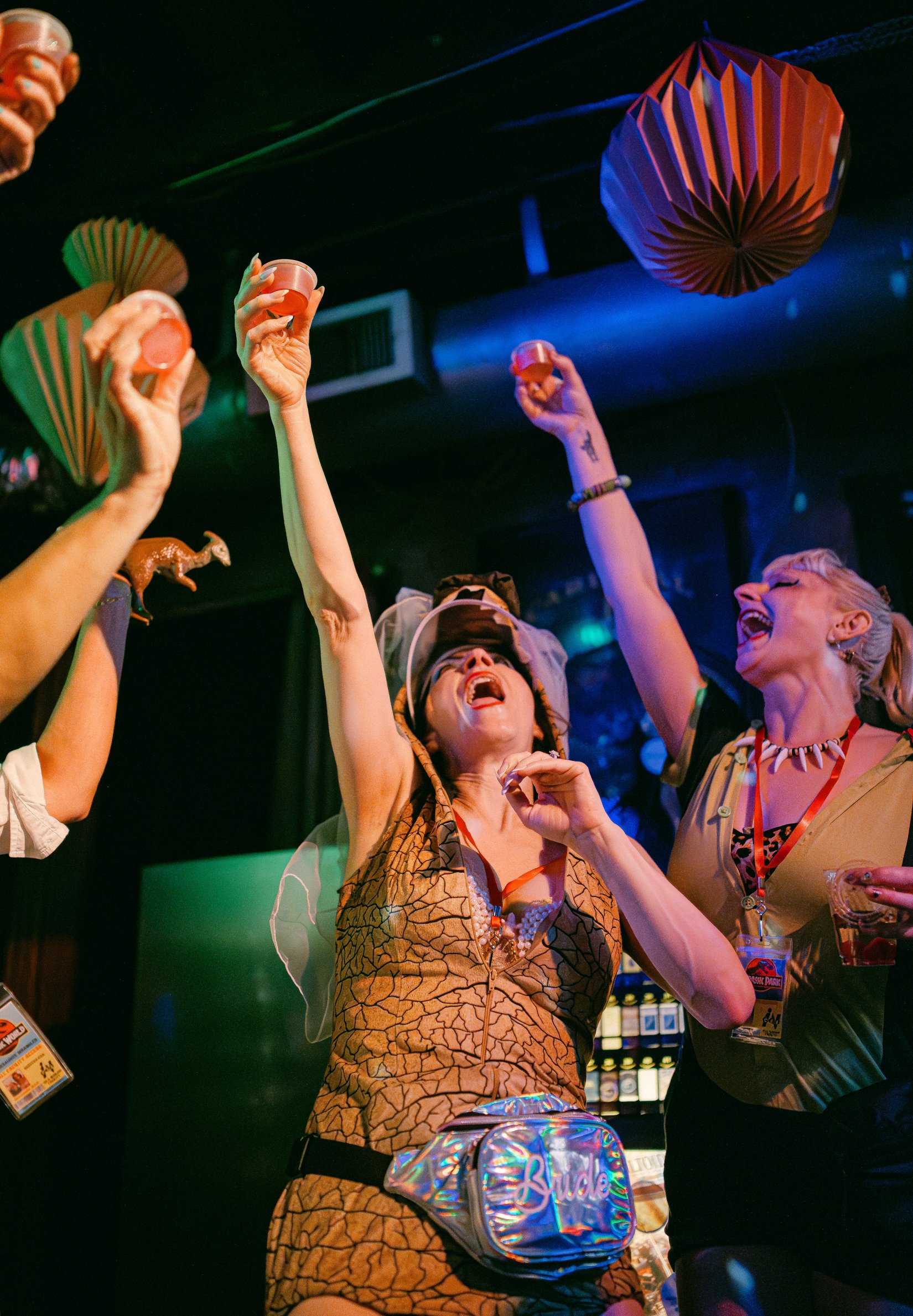 Bride and friends raising glasses at a dinosaur-themed bachelorette party in New Orleans.