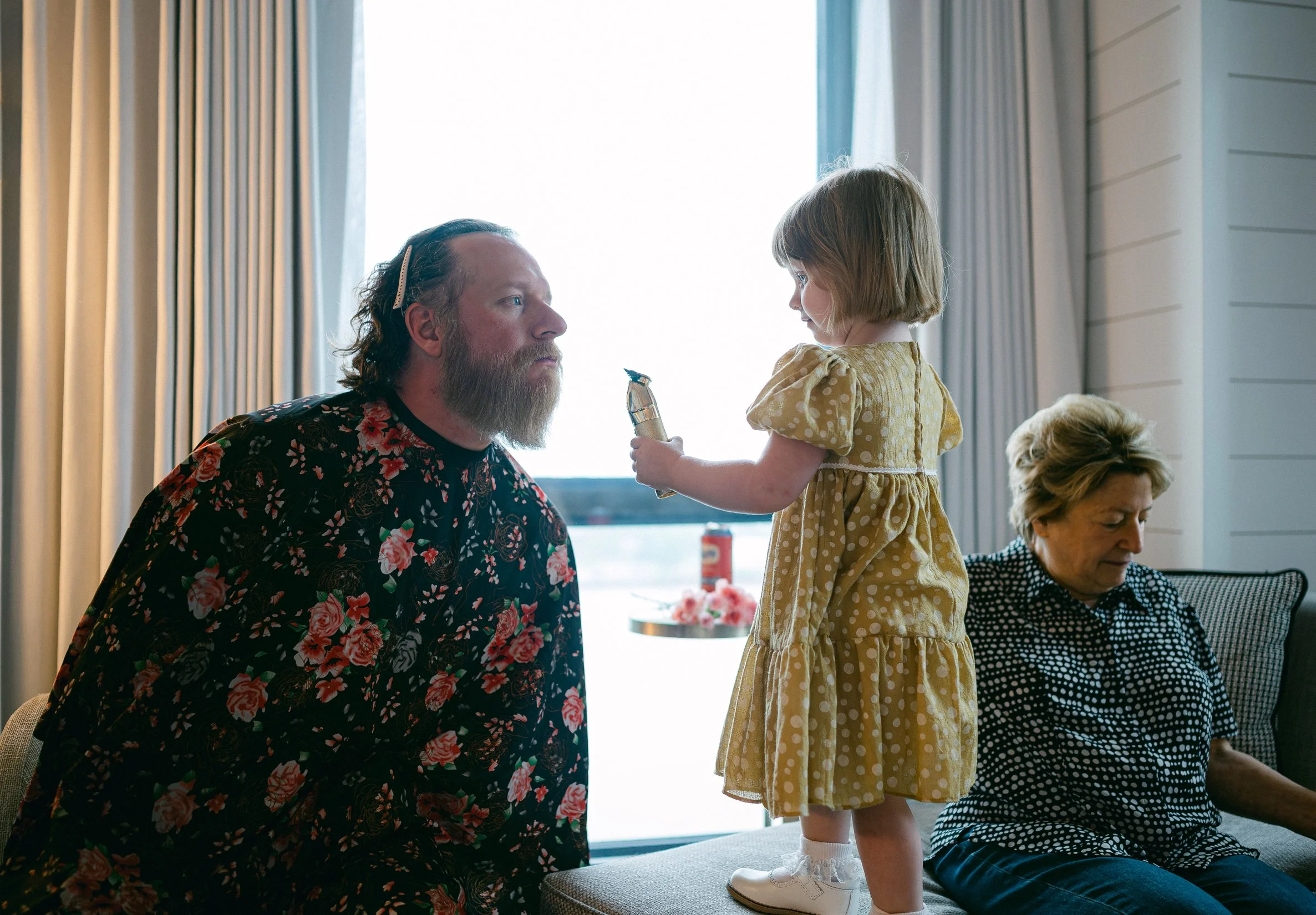 A groom pretends to allow his young daughter to cut his beard while preparing for his wedding.