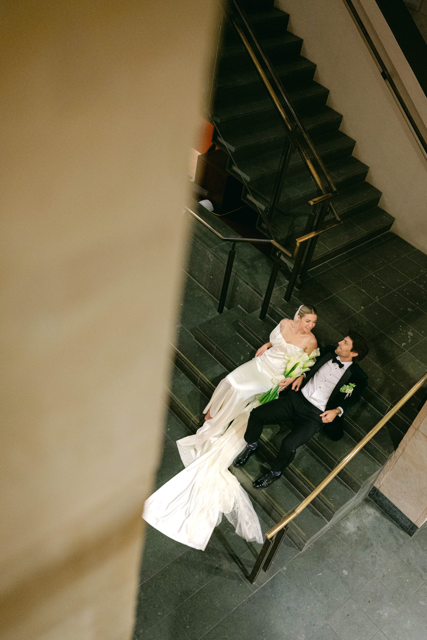 A bride and groom sitting on a staircase in the Ogden Museum in New Orleans.