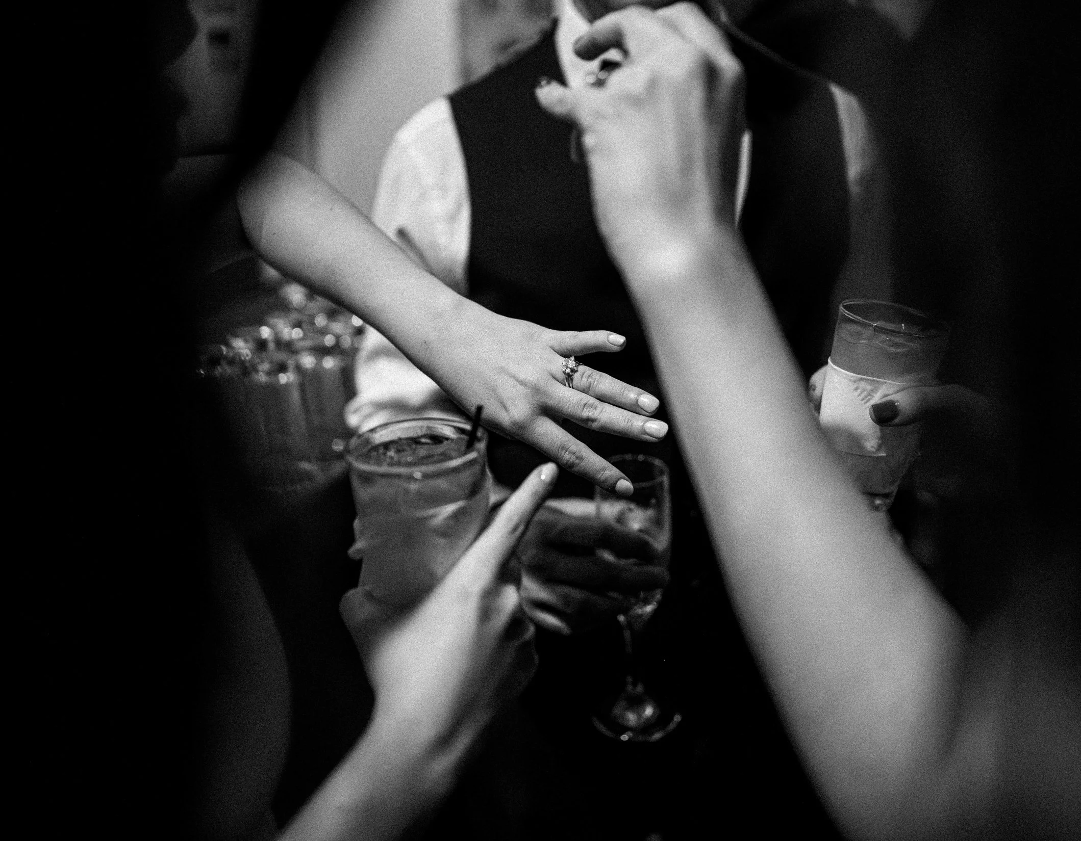 Black and white image of a bride's hand showing off her wedding ring.