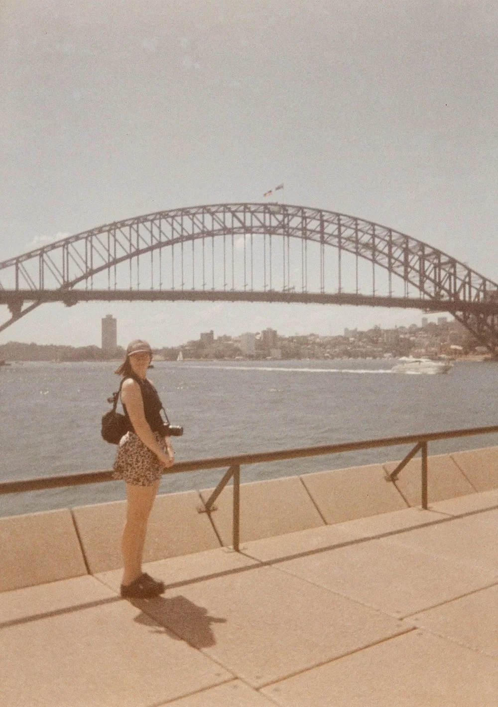 A photographer standing by a waterfront with the Sydney Harbour Bridge in the background.