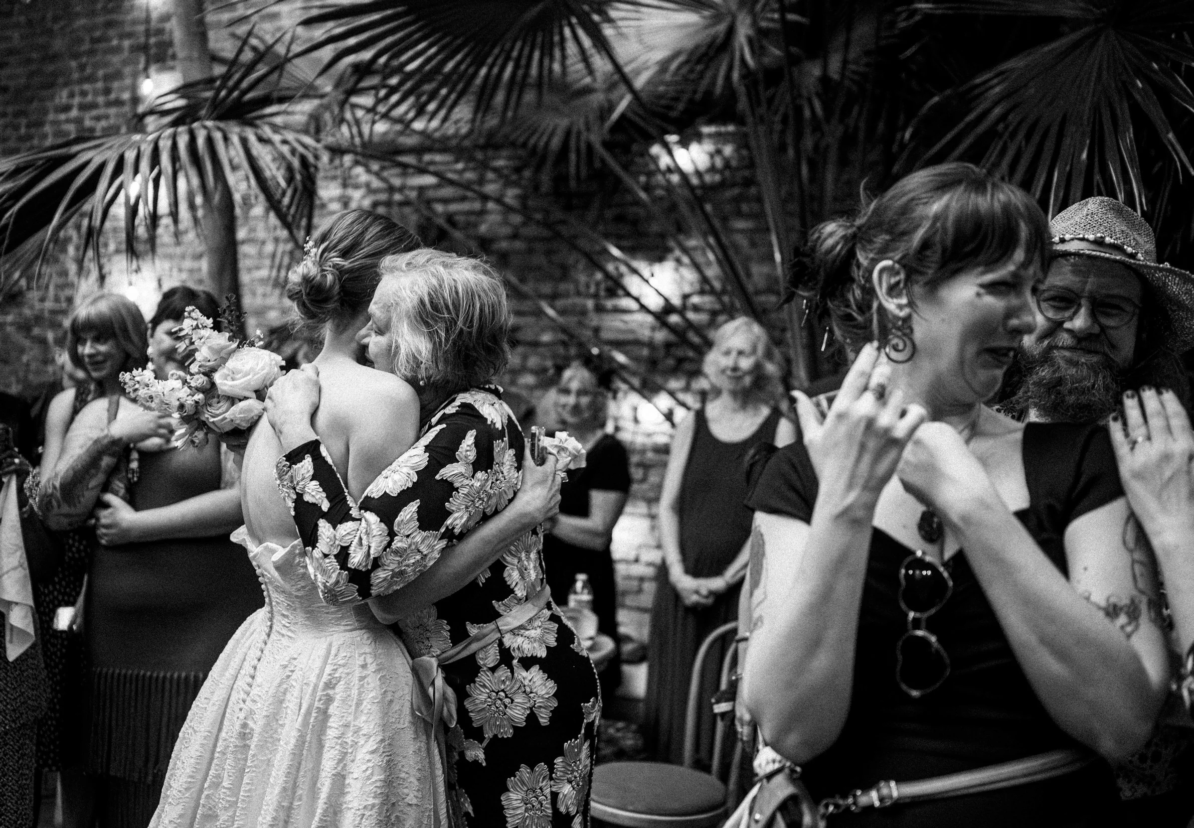 A bride and her mother hug tightly at her wedding in a New Orleans courtyard.