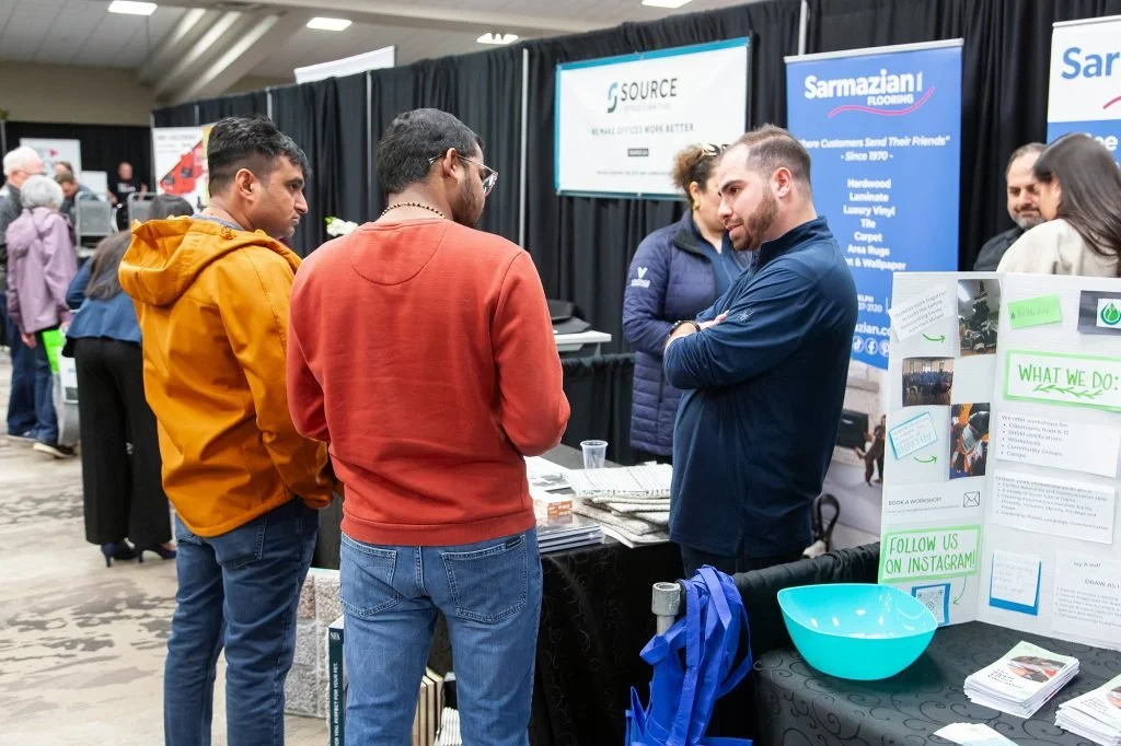People at a booth talking with a representative at a trade show or conference.
