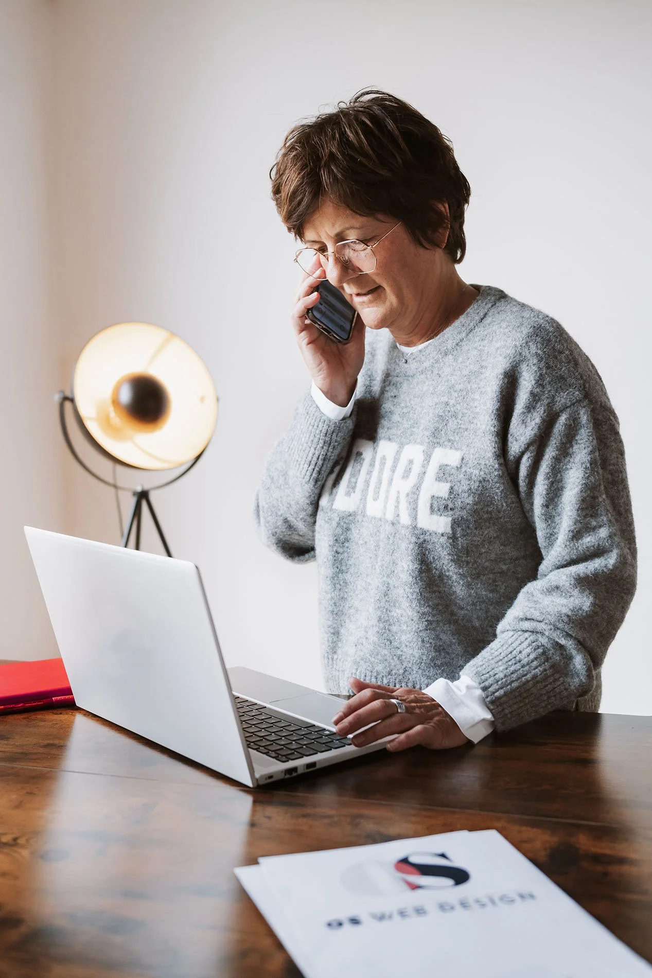 Onika telefoniert während sie am Laptop an einem Tisch arbeitet.