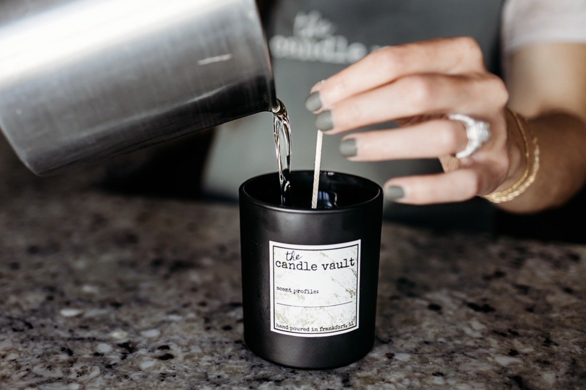 A candle being poured. The words 'the candle vault' can be seen on the candle jar.