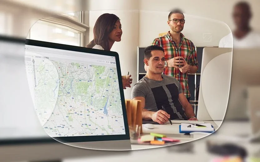People working at a desk in front of a computer monitor, the working distance occupational lenses are made for