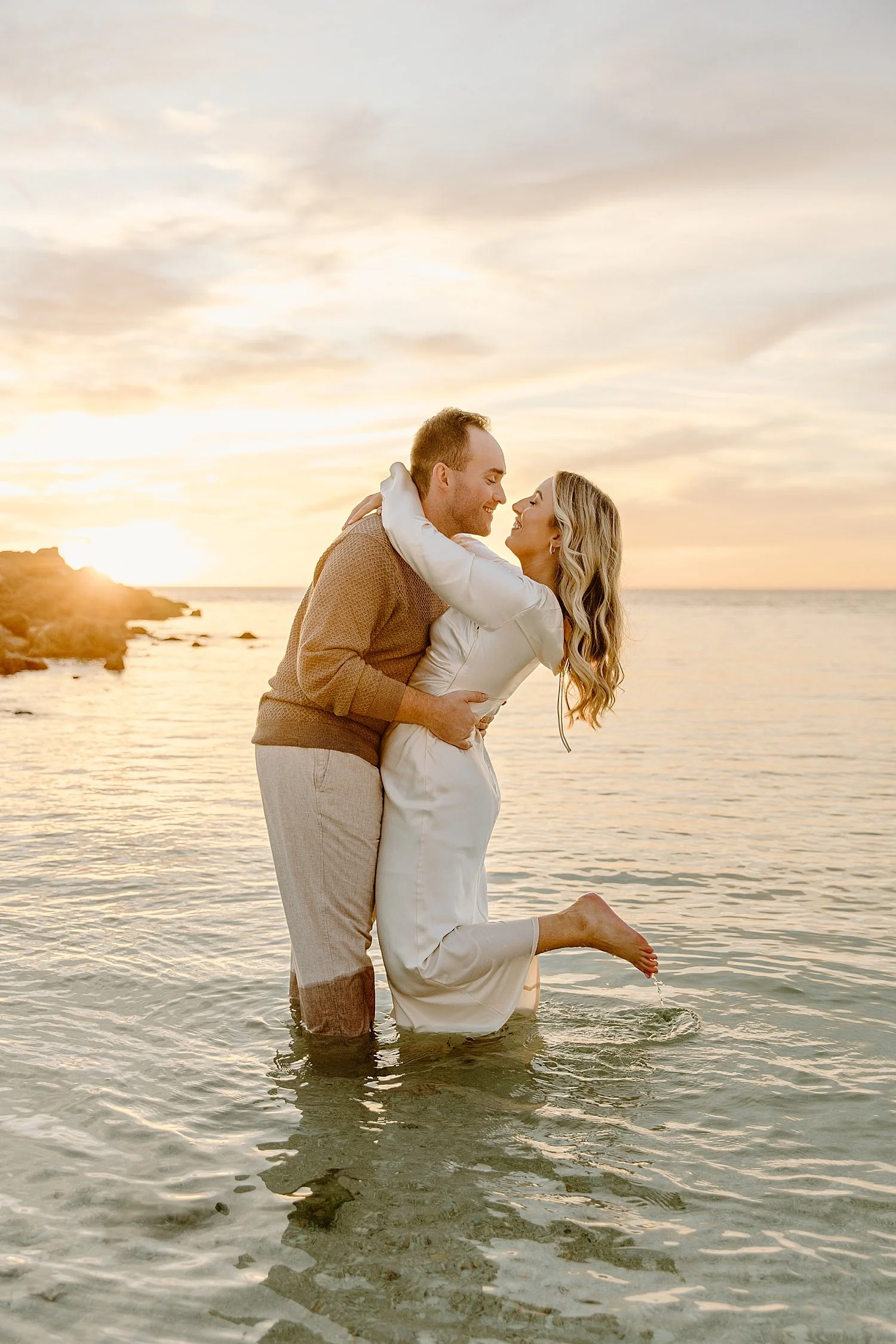 man holds his wife close in the ocean water by Florida wedding photographer
