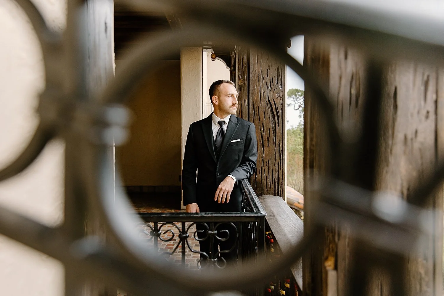 groom stands on balcony by Florida wedding photographer