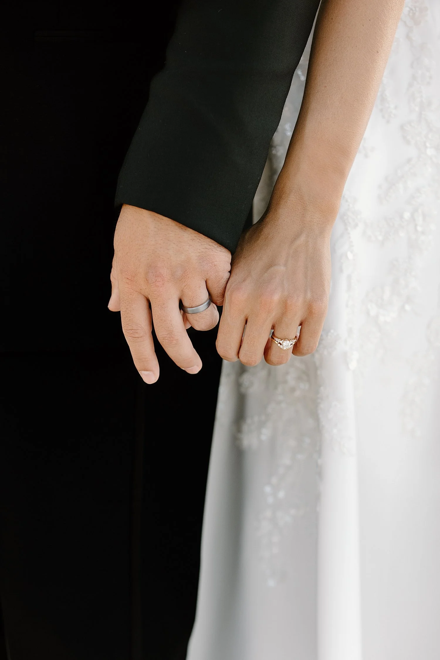 newlyweds hold each other’s fingers with new rings by Florida Wedding Photographer