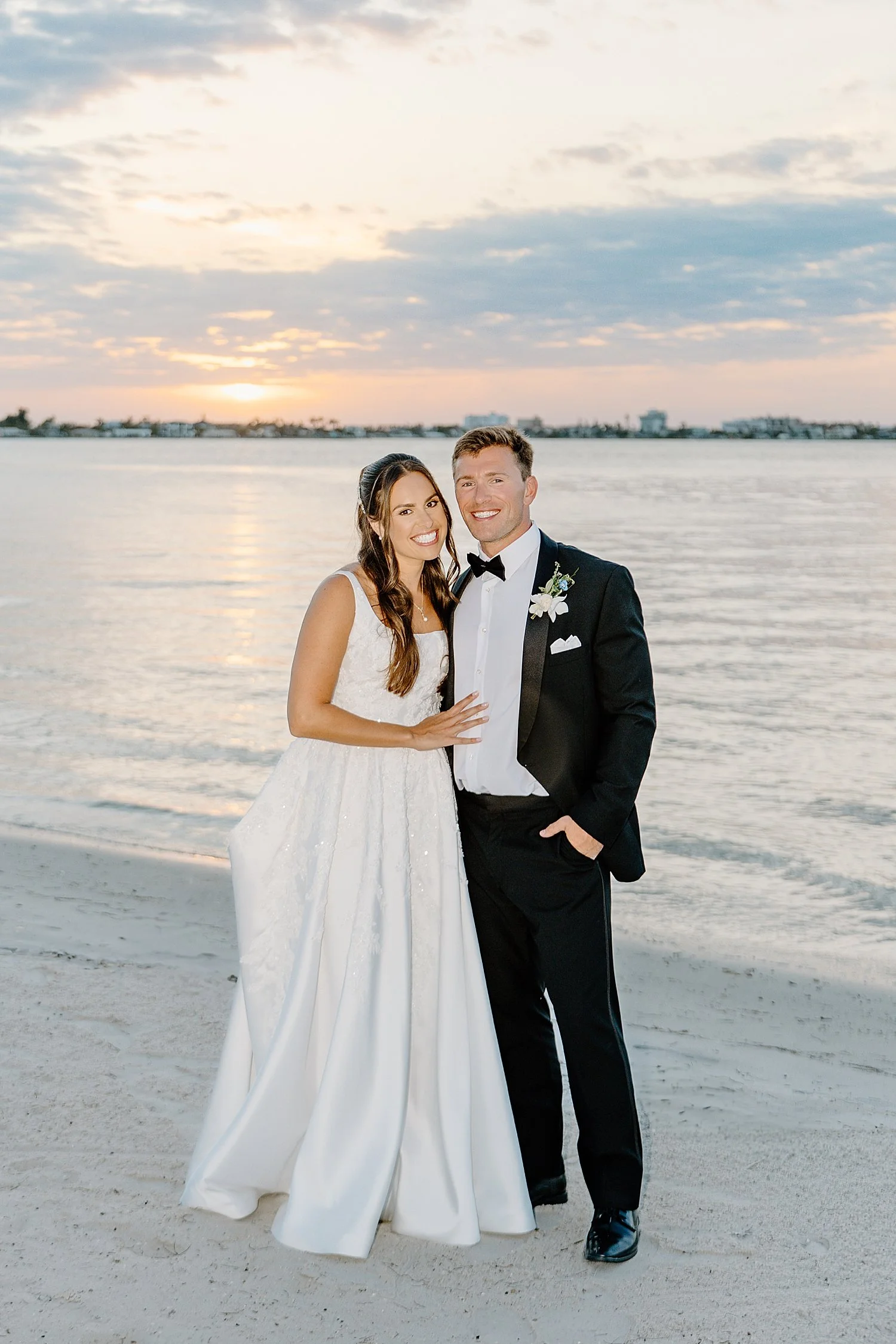 newlyweds embrace during golden hour on beach at Isla Del Sol Yacht and Country Club