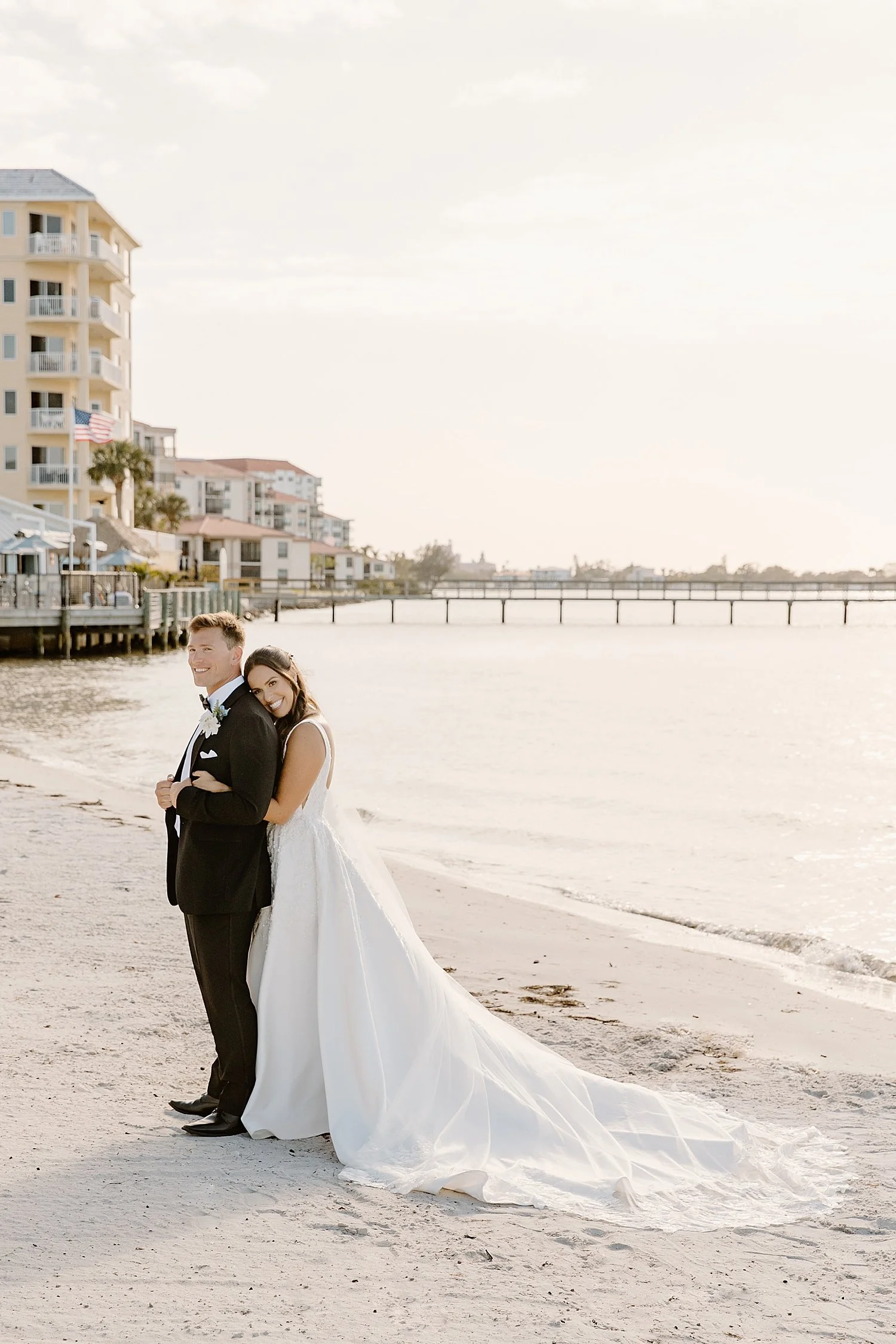 brunette wraps up her man in hug on the beach by Florida Wedding Photographer