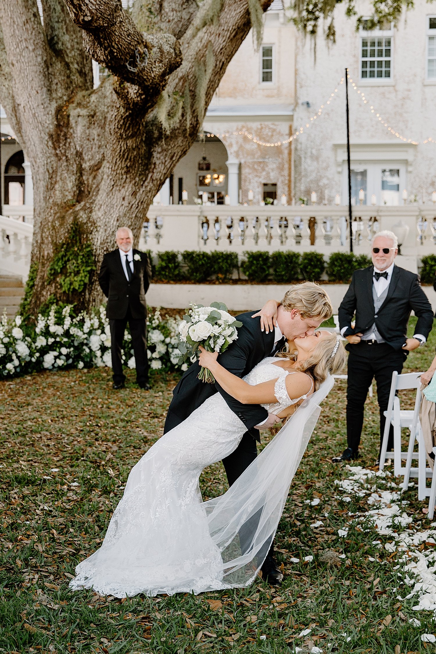  newlyweds dip for a kiss at the end of the aisle at Bella Cosa 