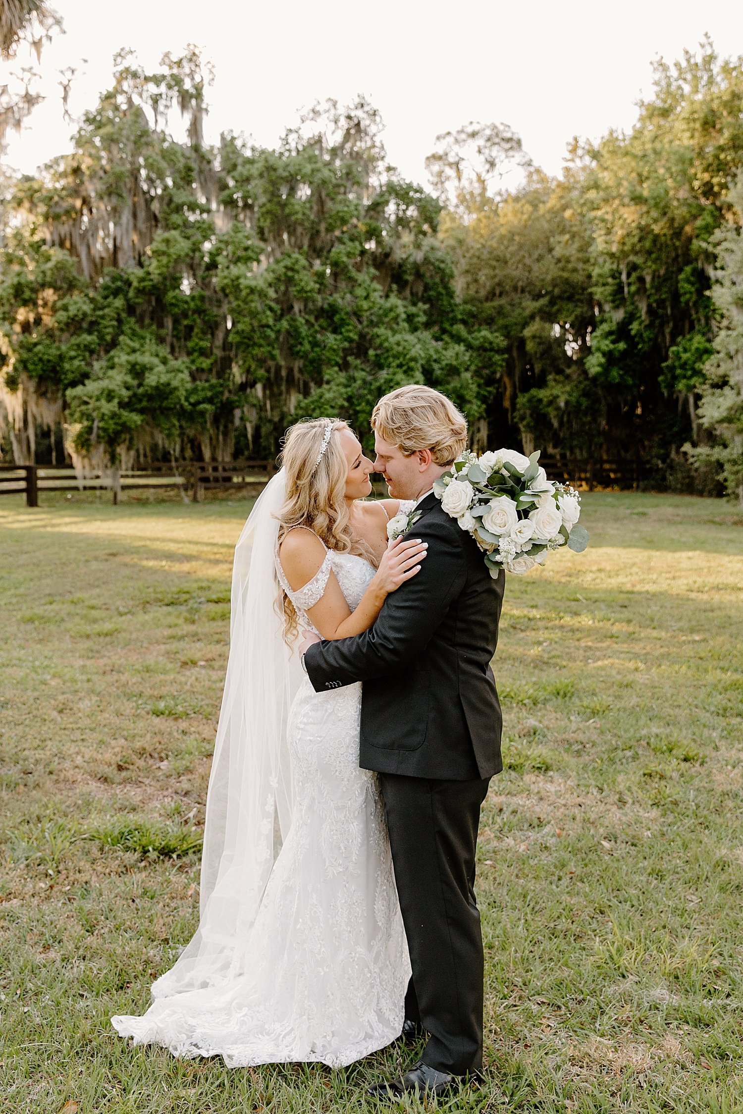  man and woman stand face to face in formal attire on lawn by Florida wedding photographer 