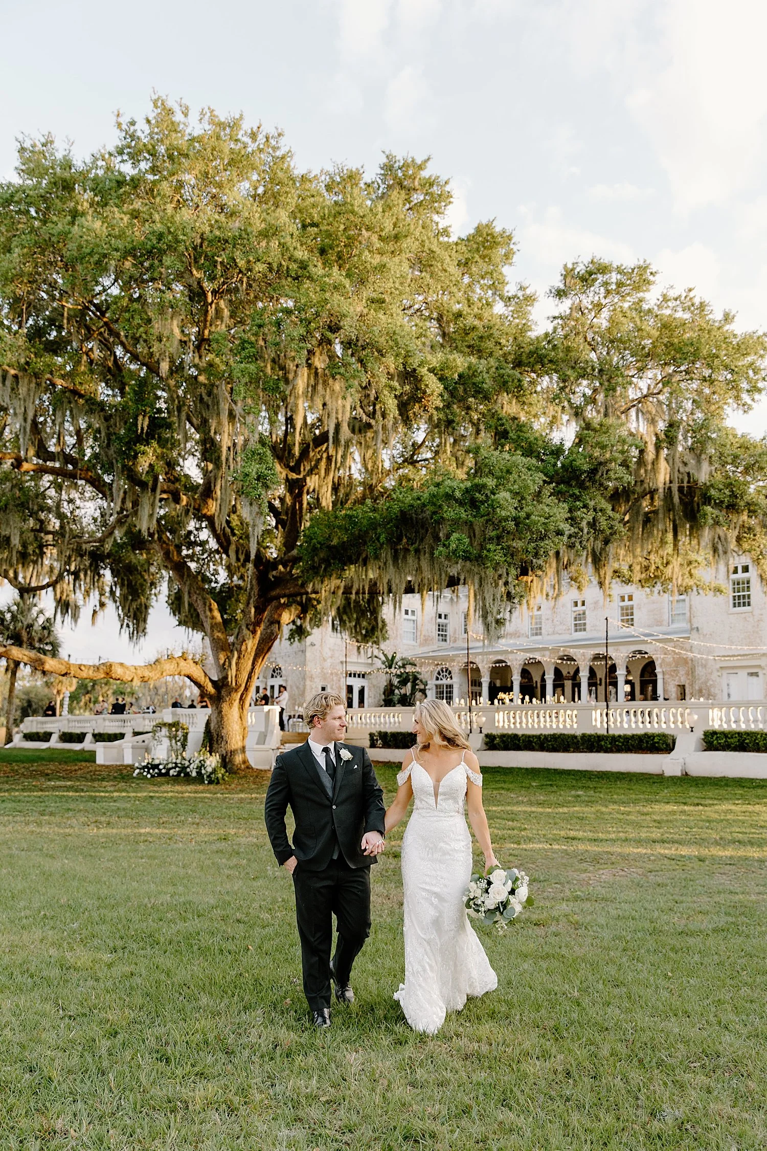  newlyweds walk across the lawn at Bella Cosa before reception 