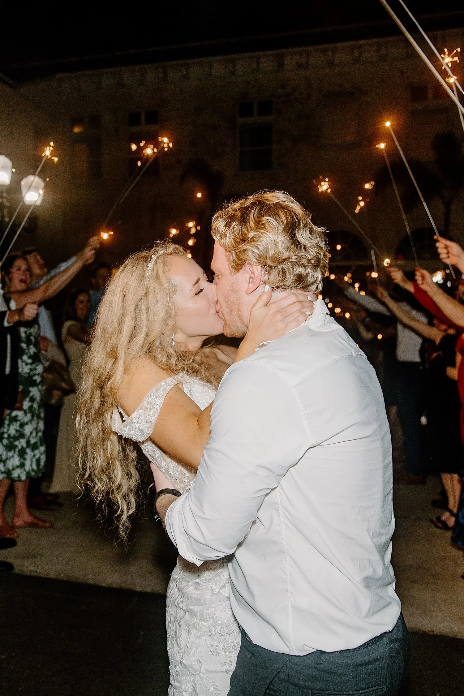  newlyweds share a kiss during their sparkler exit at Bella Cosa 