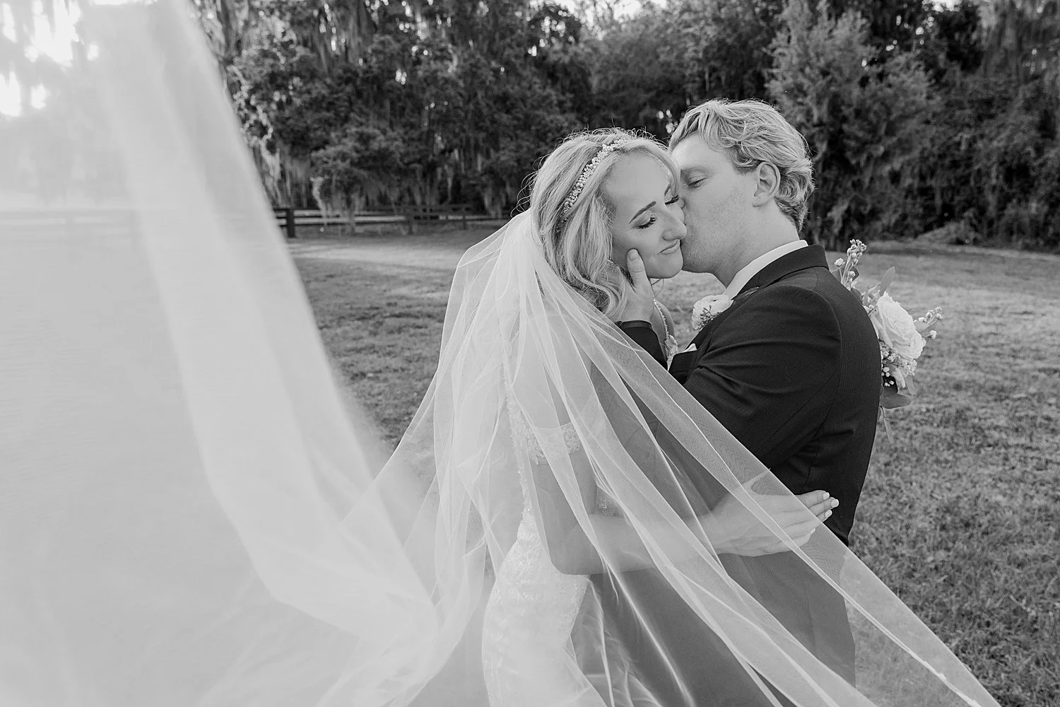  man kisses his brides cheek under her swooping veil by Taylor Shea Photo 